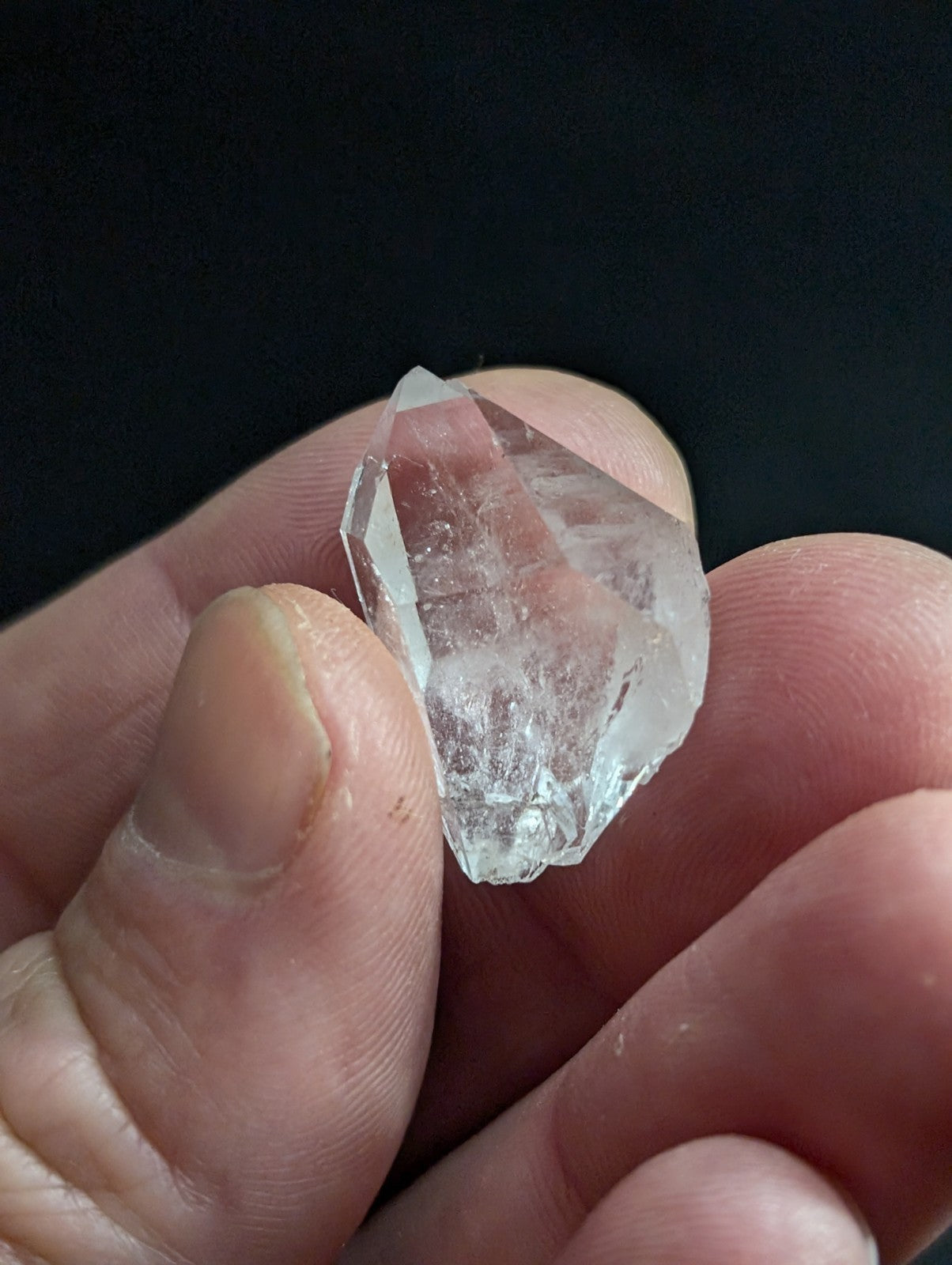 A clear, faceted quartz crystal with a pointed tip and natural internal inclusions.