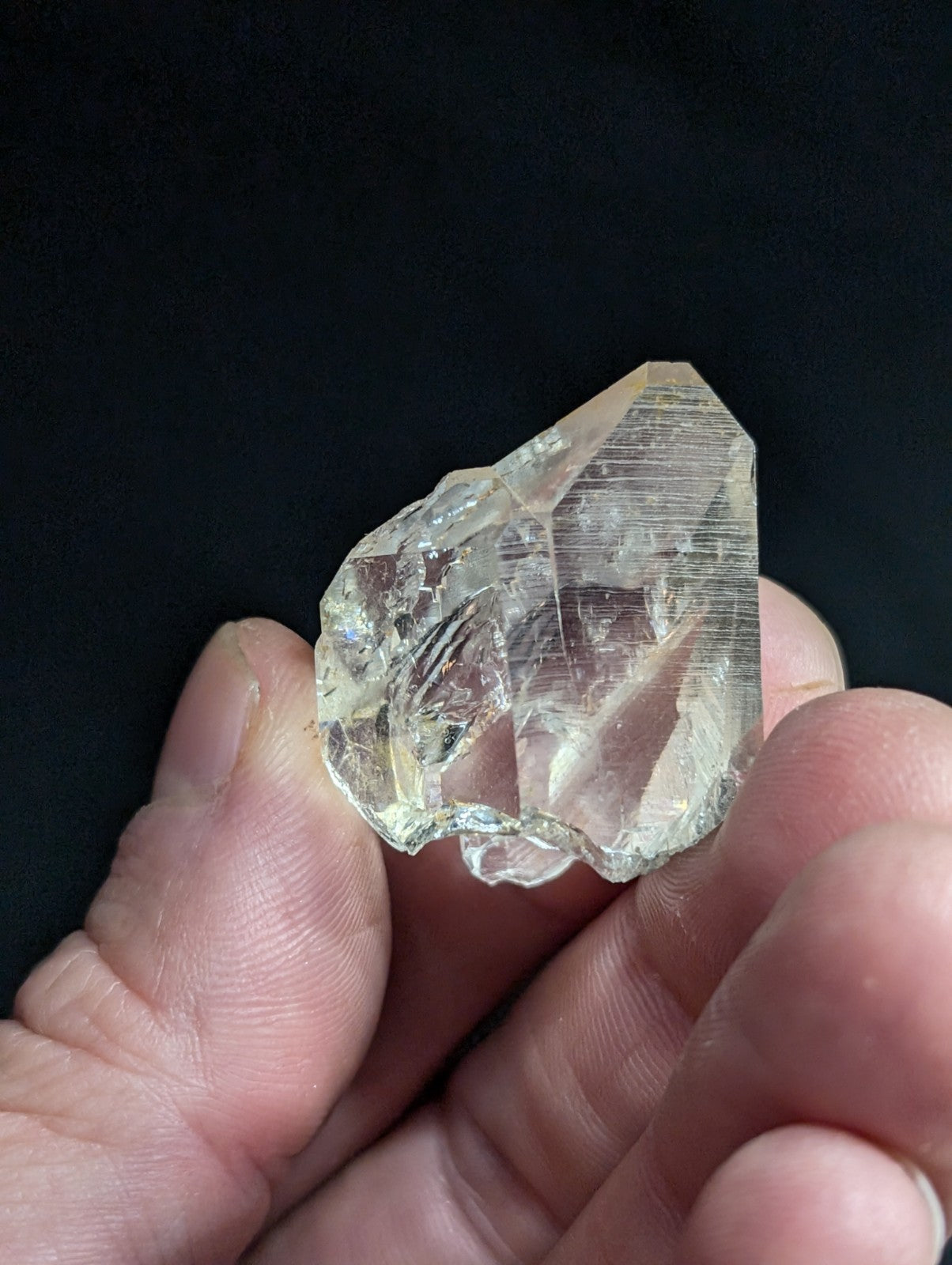 A translucent, clear quartz crystal with a pointed tip and natural facets.