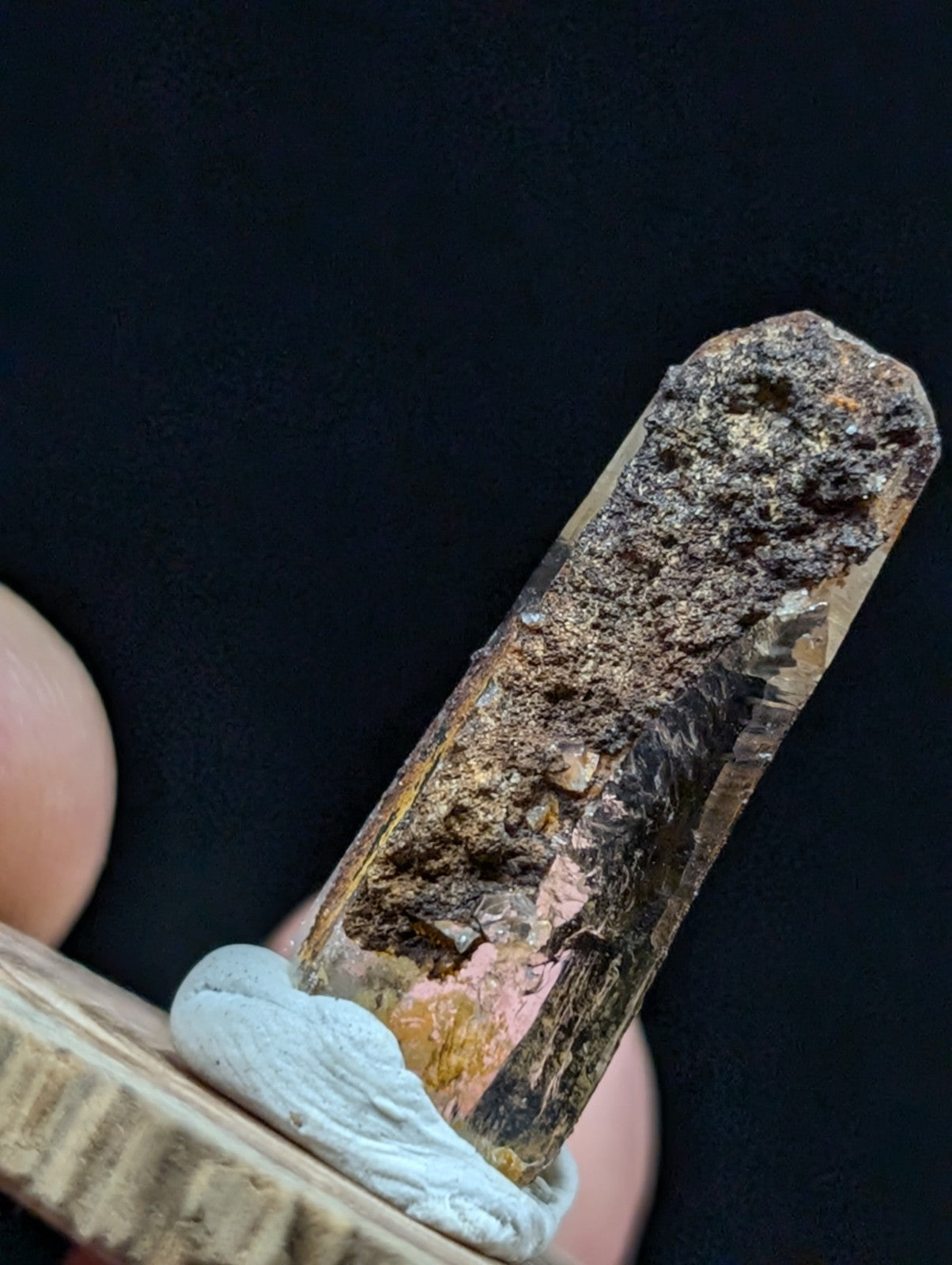 A translucent amber-colored crystal with a rough, earthy top and visible internal inclusions.