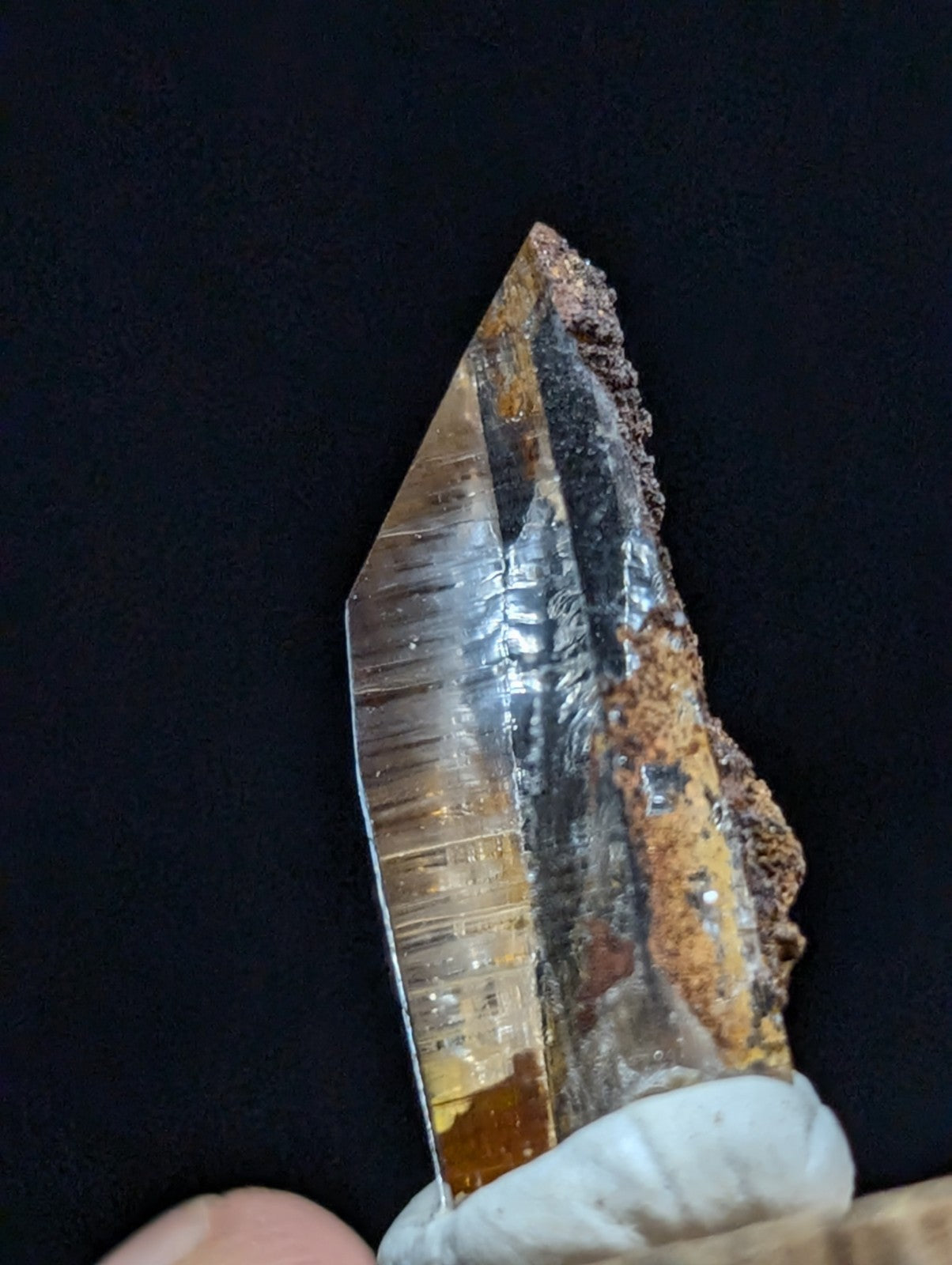A translucent, amber-hued quartz crystal with a sharp point and visible internal striations.