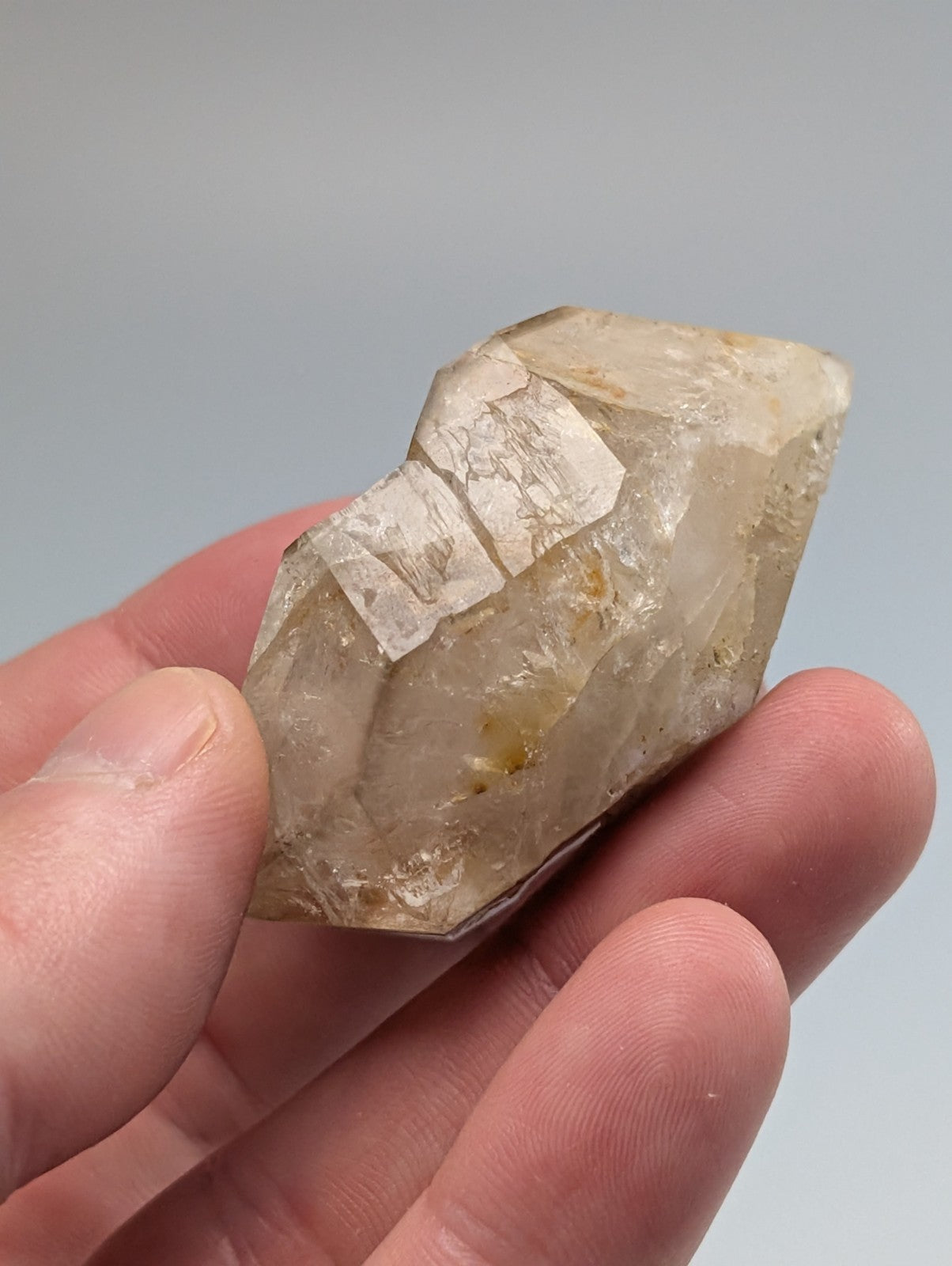 A translucent, pale yellowish quartz crystal with visible internal inclusions and a faceted surface.