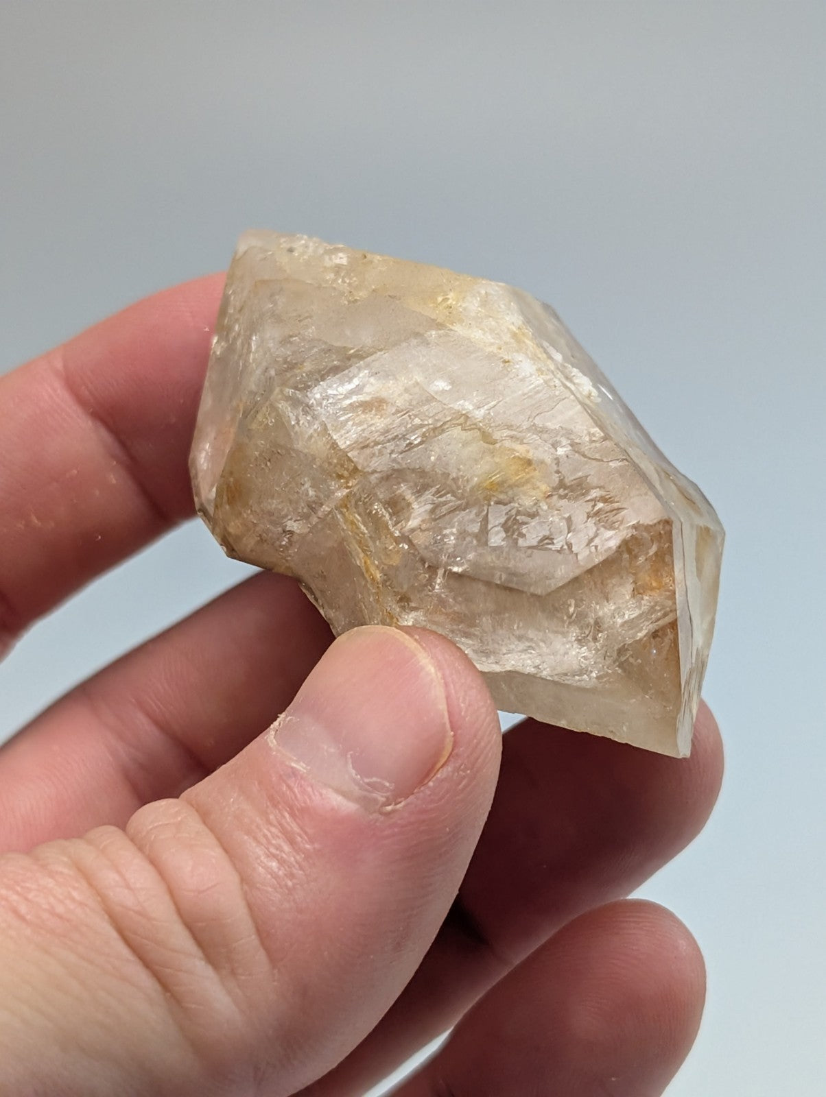 A translucent, pale yellow crystal with visible internal inclusions and a faceted surface.