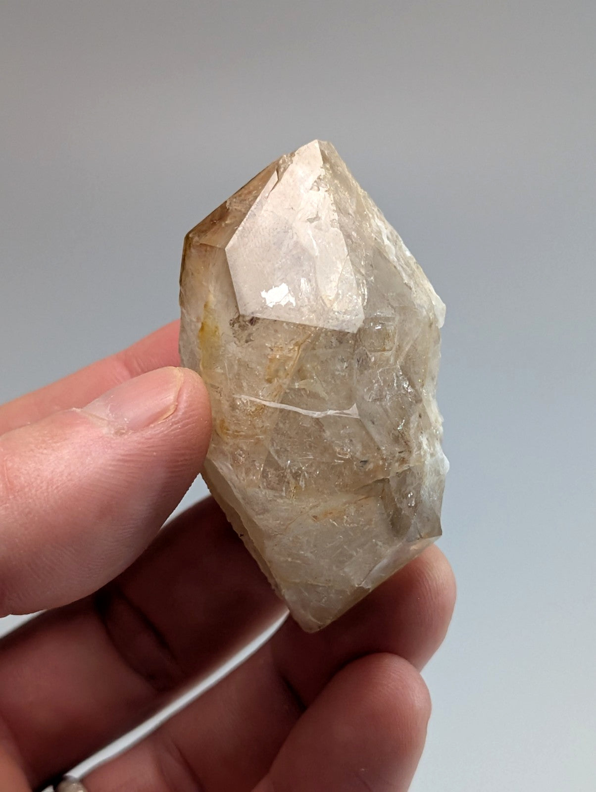 A translucent, faceted quartz crystal with a pale yellowish tint and visible internal inclusions.