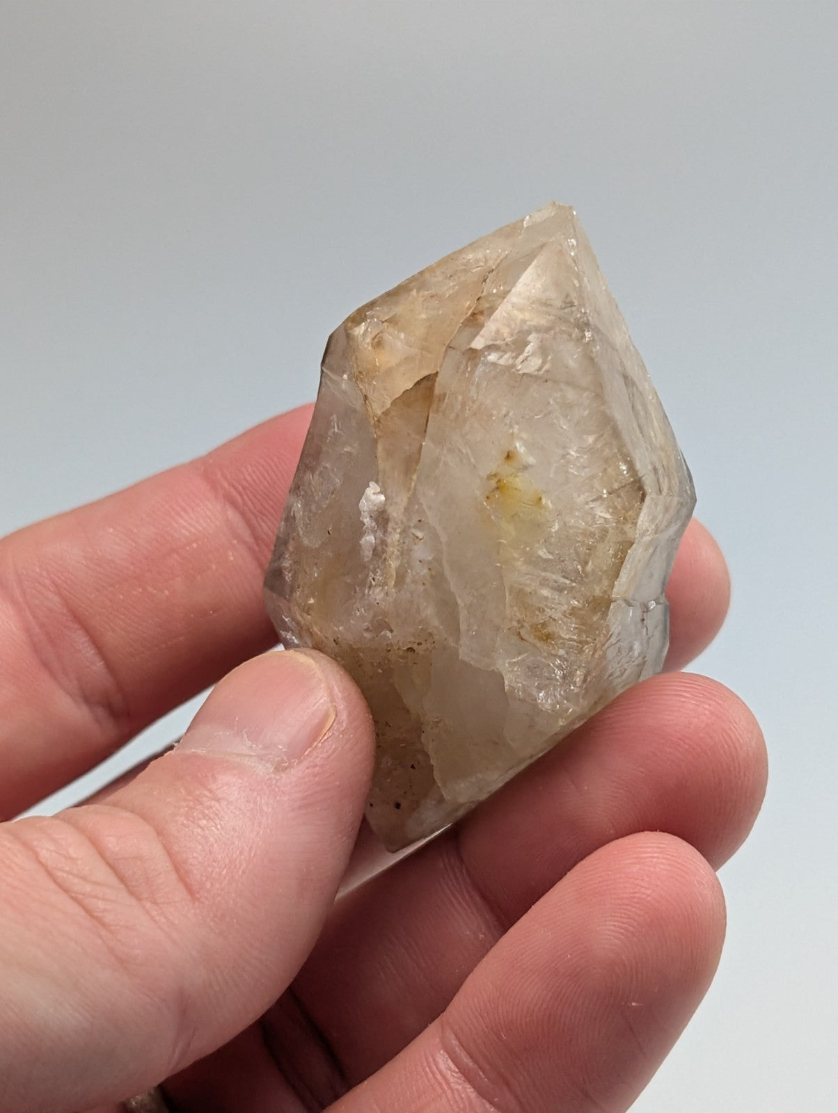 A translucent, pale quartz crystal with natural inclusions and a pointed, faceted top.