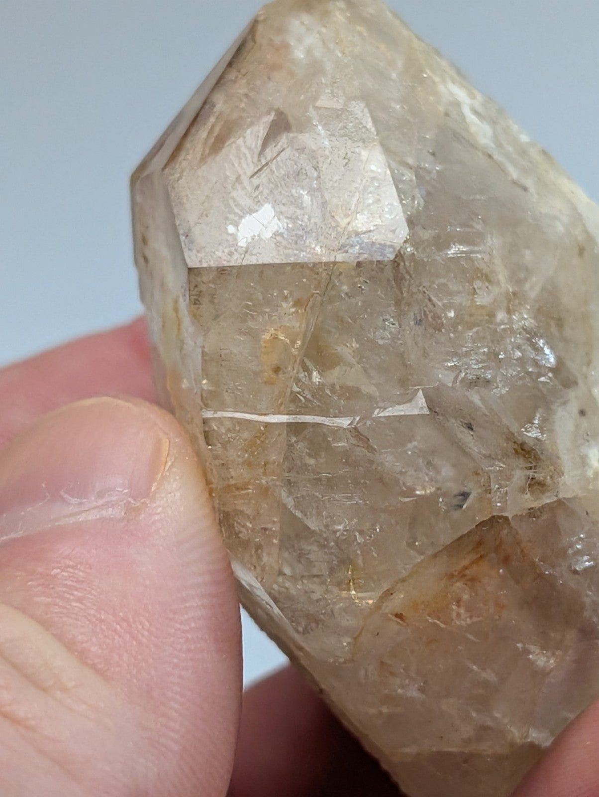 A translucent, light brown quartz crystal with a faceted surface and visible internal inclusions.