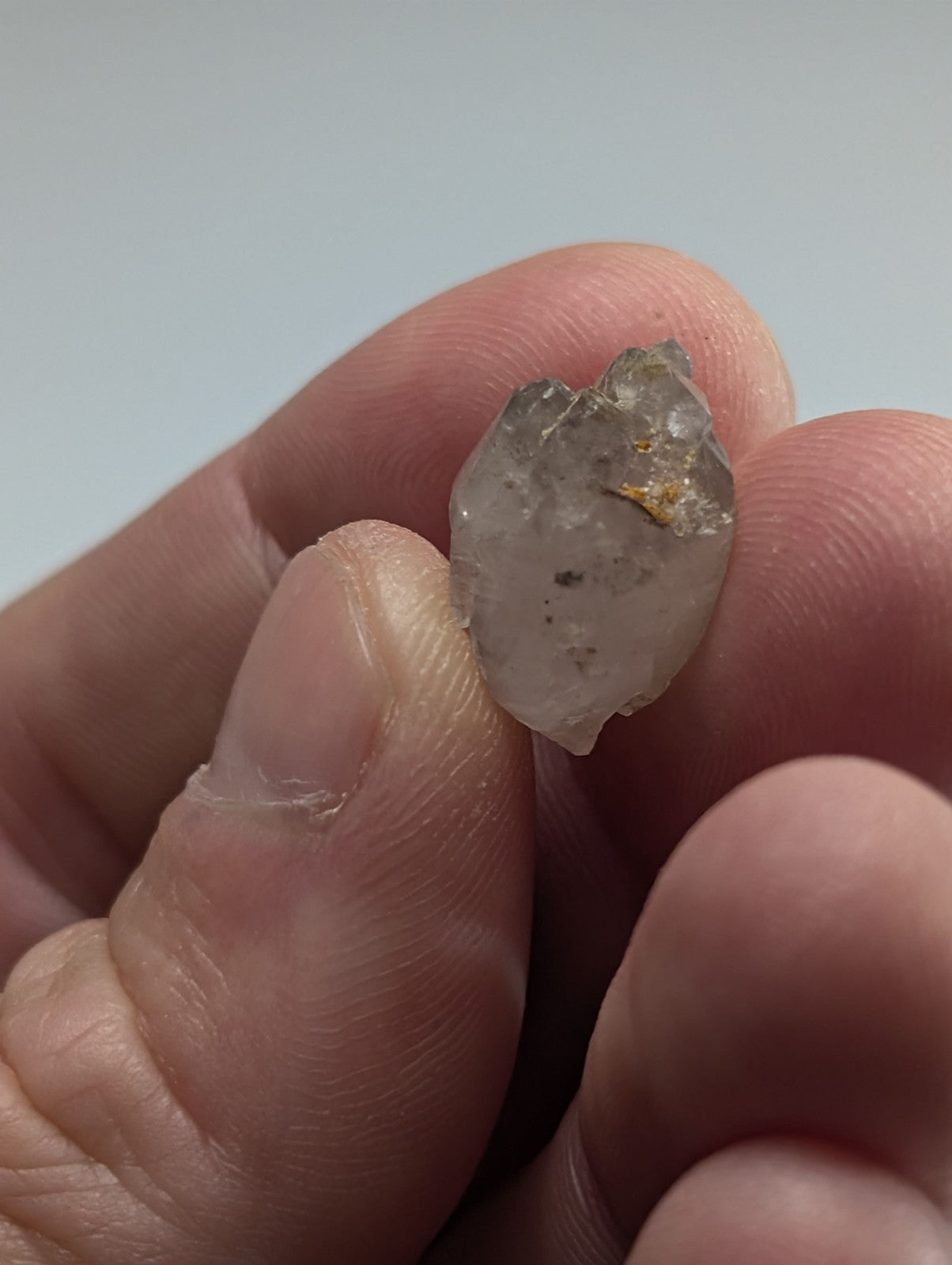 A translucent, irregularly shaped quartz crystal with subtle golden inclusions and a slightly rough, natural surface.