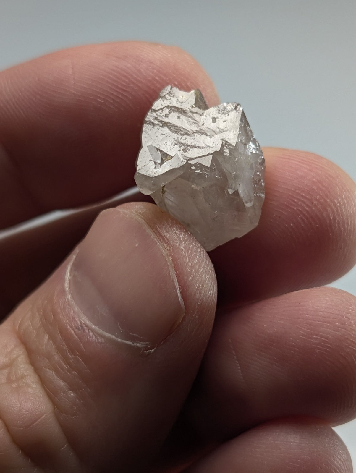 A rough, translucent quartz crystal with a silver-tinged surface and jagged edges.