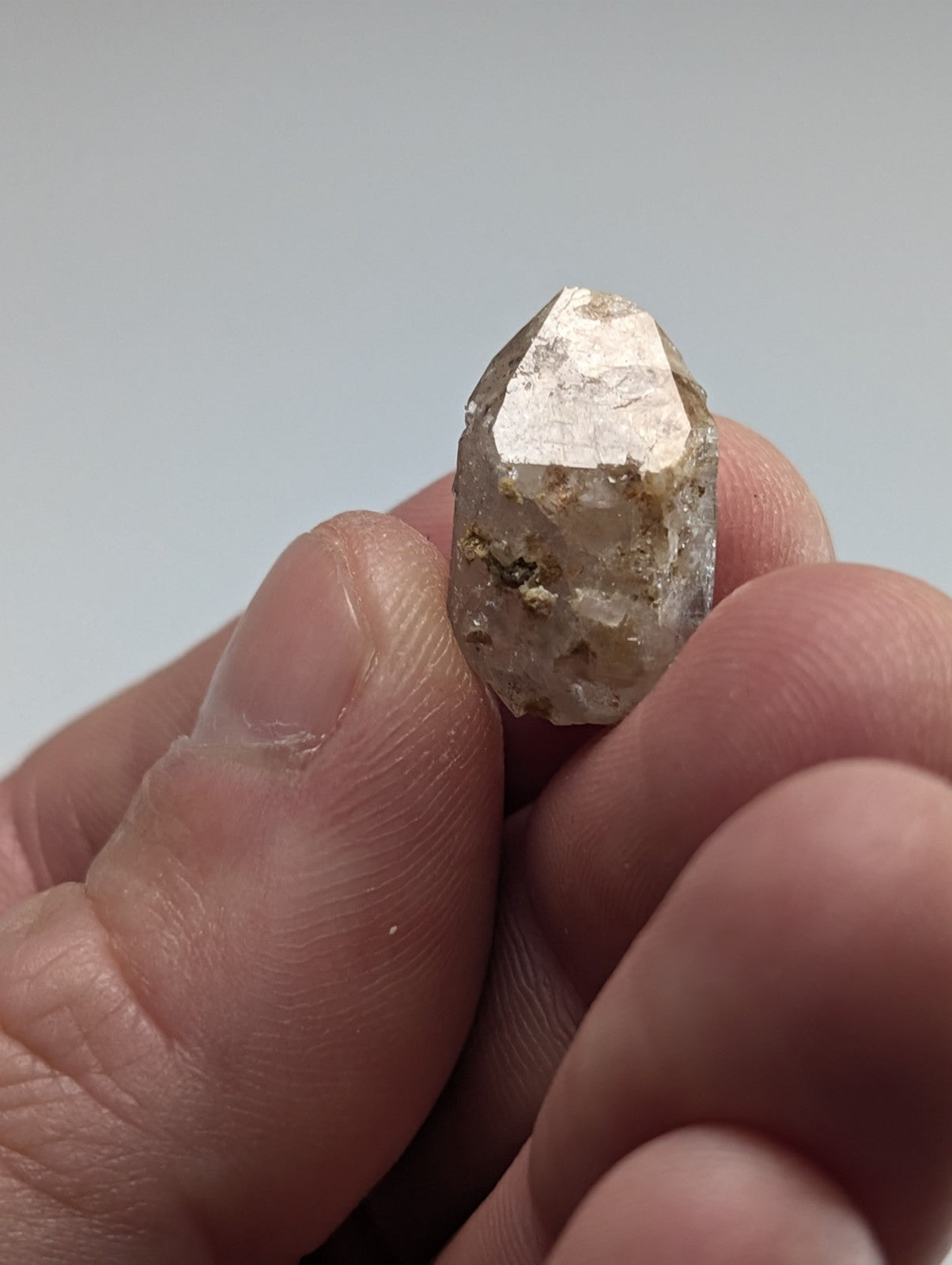 A translucent, faceted quartz crystal with a pale, milky hue and subtle brown inclusions.