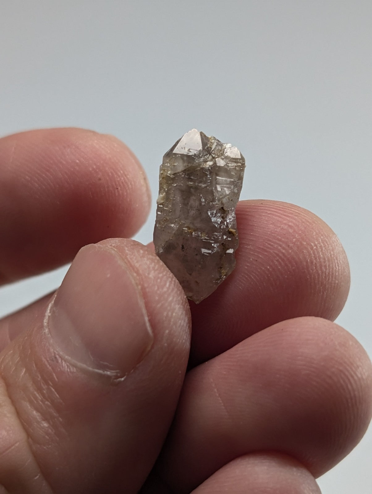 A translucent, faceted quartz crystal with a slightly cloudy grayish hue and visible internal inclusions.