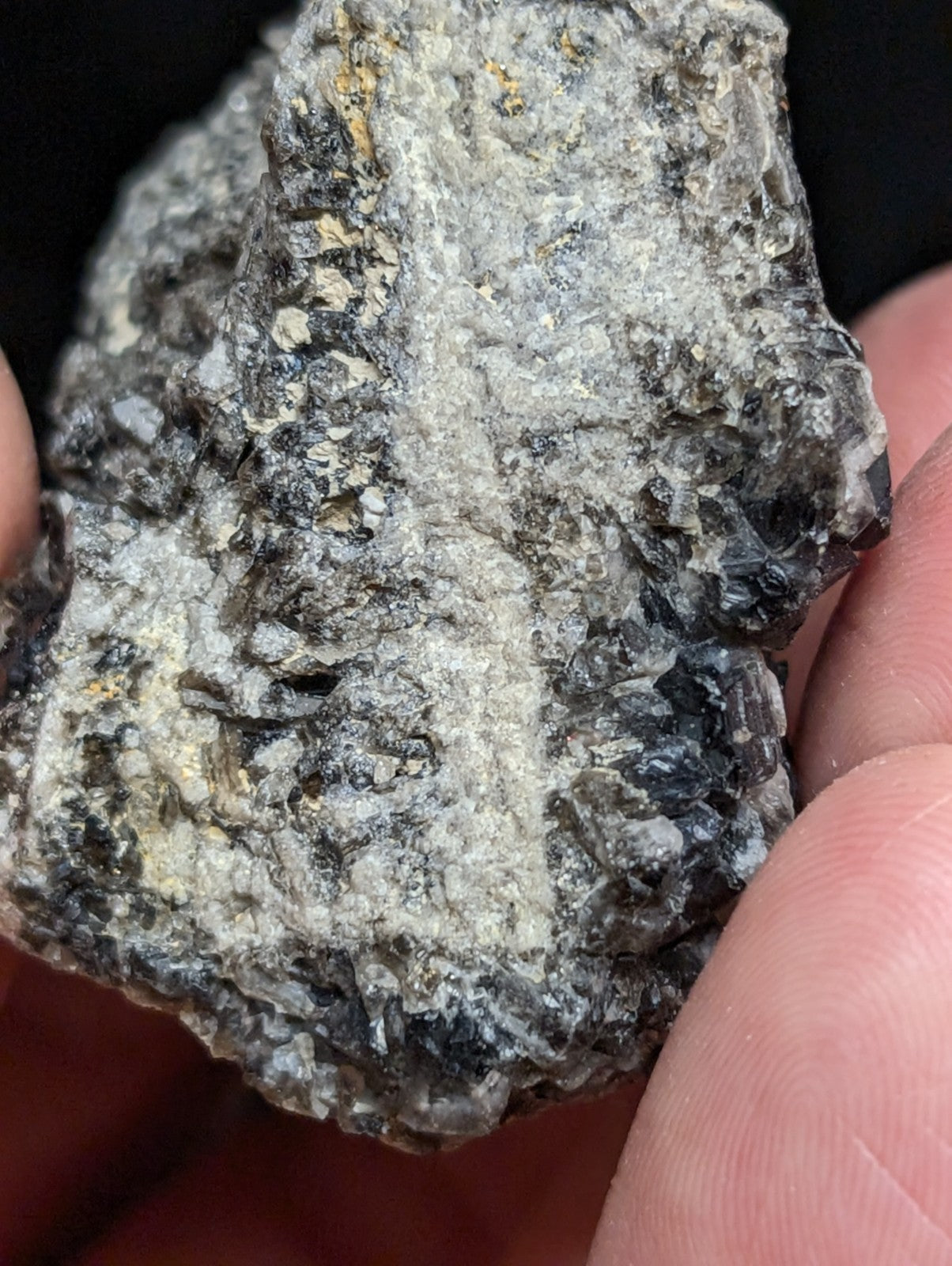 A rough, irregularly shaped gray rock with speckles of black and faint golden flecks.