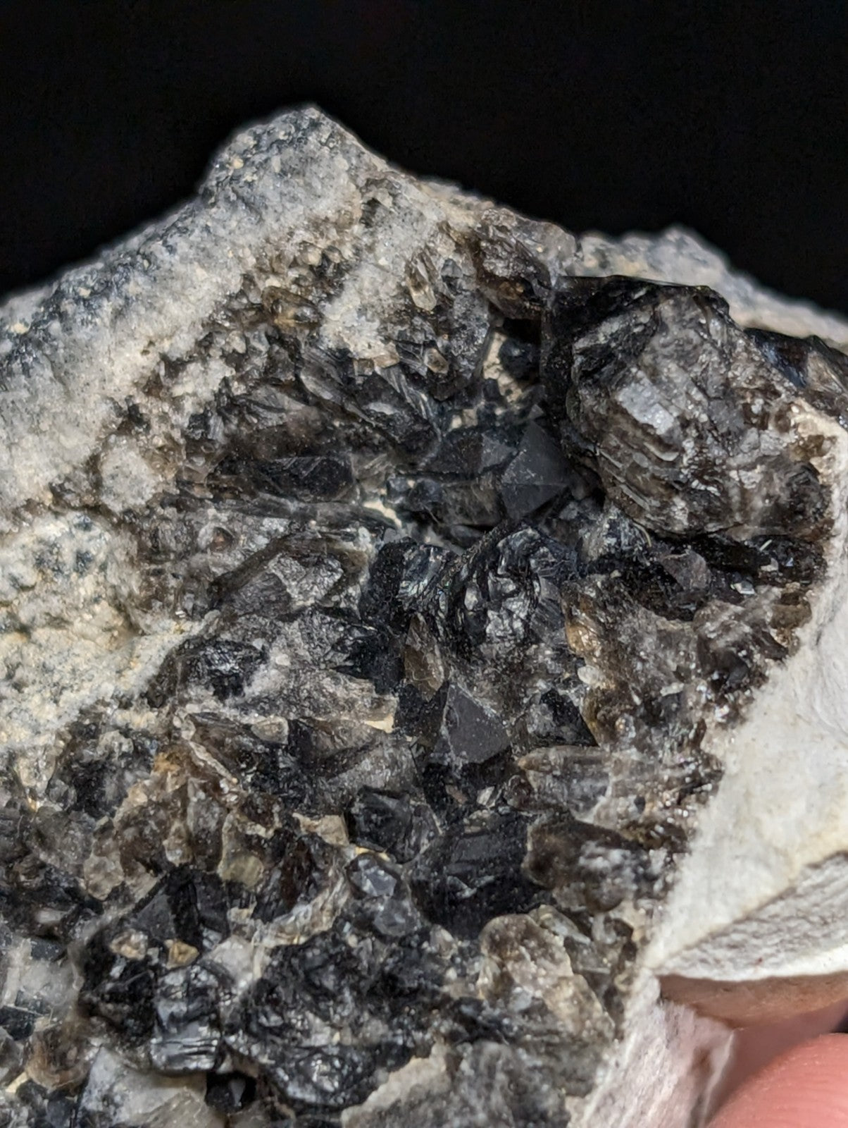 A rugged black and gray mineral specimen with sharp, crystalline formations embedded in a rough-textured matrix.
