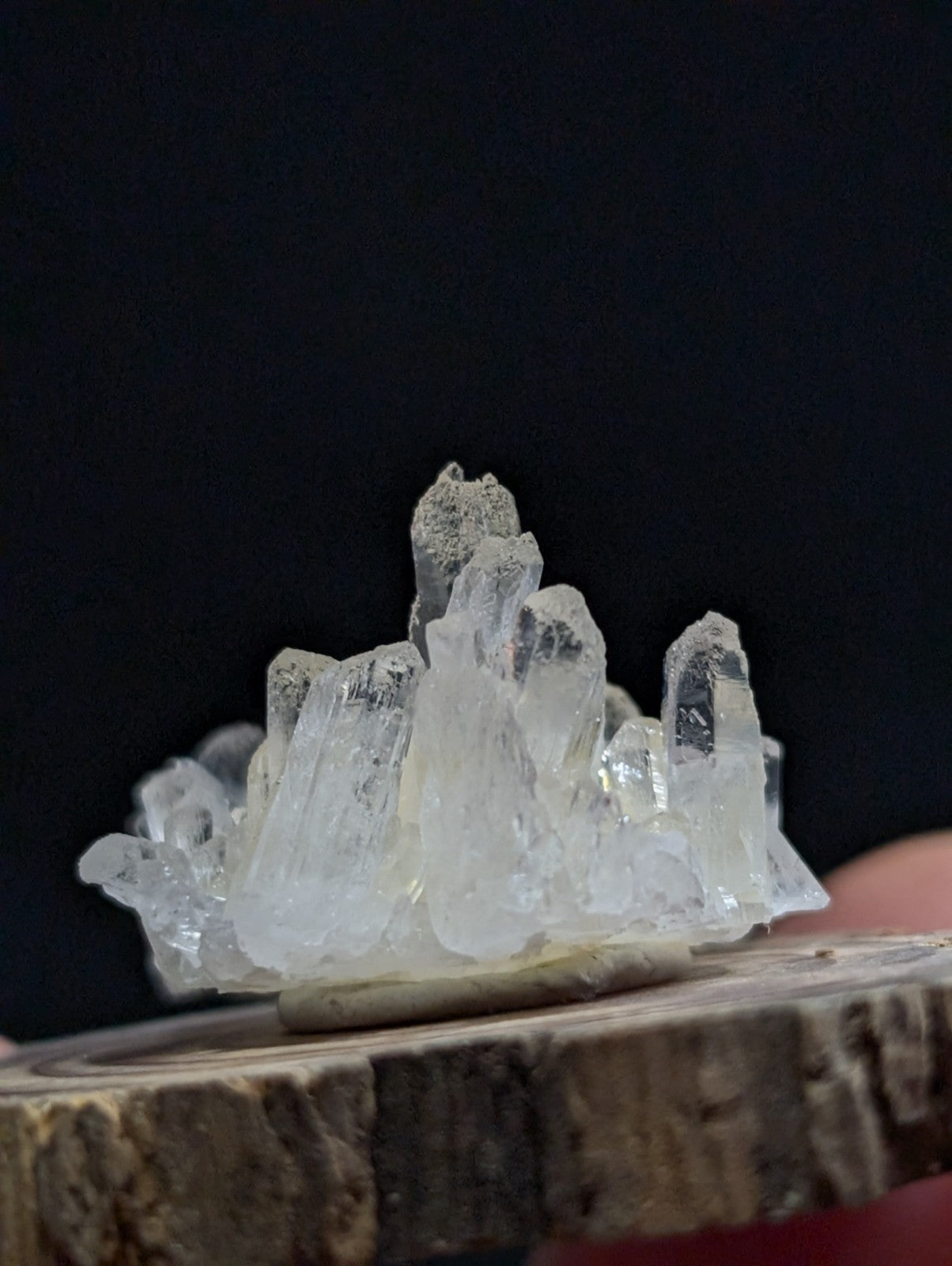 A translucent, clear quartz crystal cluster with jagged edges and a natural, earthy base.