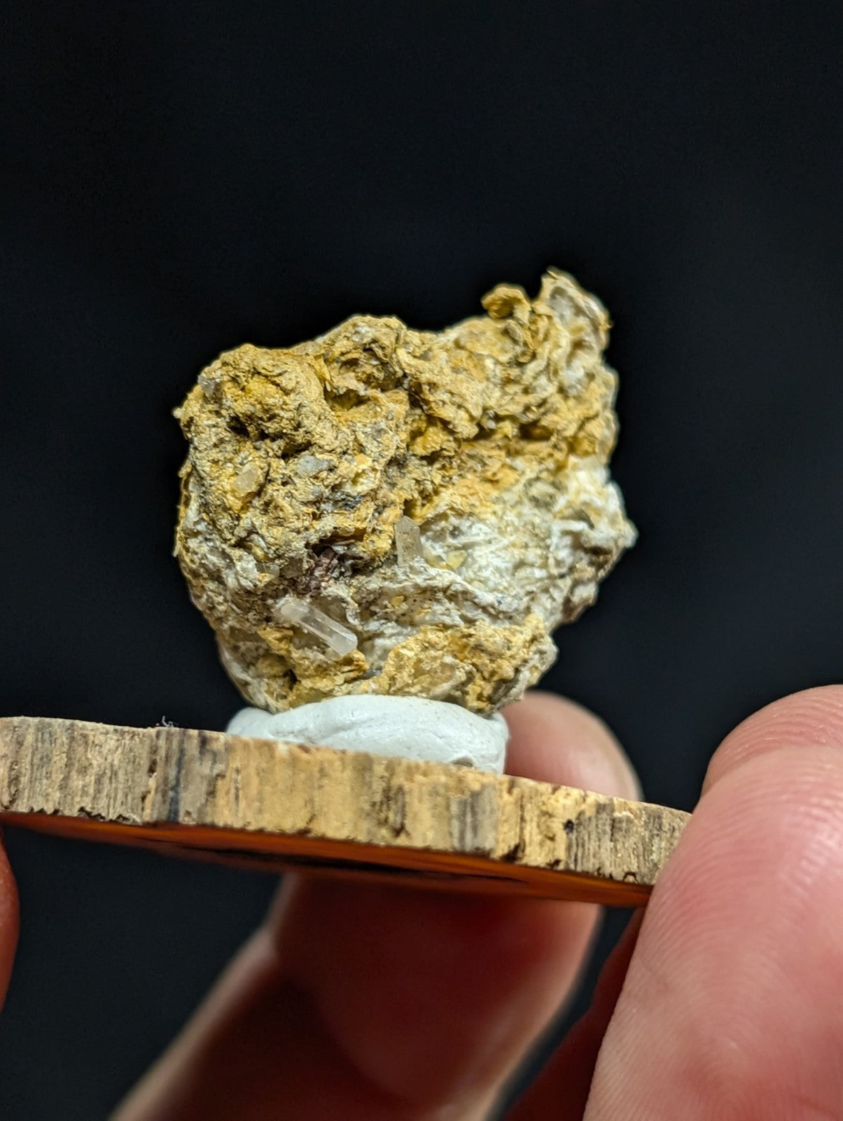 A rough, irregularly shaped mineral specimen with a golden-yellow and white crystalline surface.