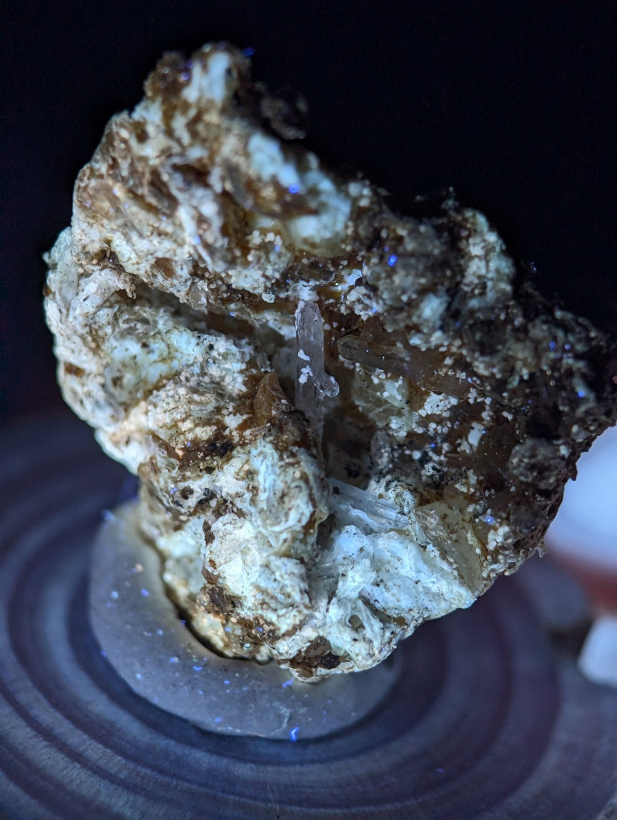 A rugged, irregularly shaped mineral specimen with a mix of white and brown hues, featuring translucent crystalline formations embedded in its rocky matrix.