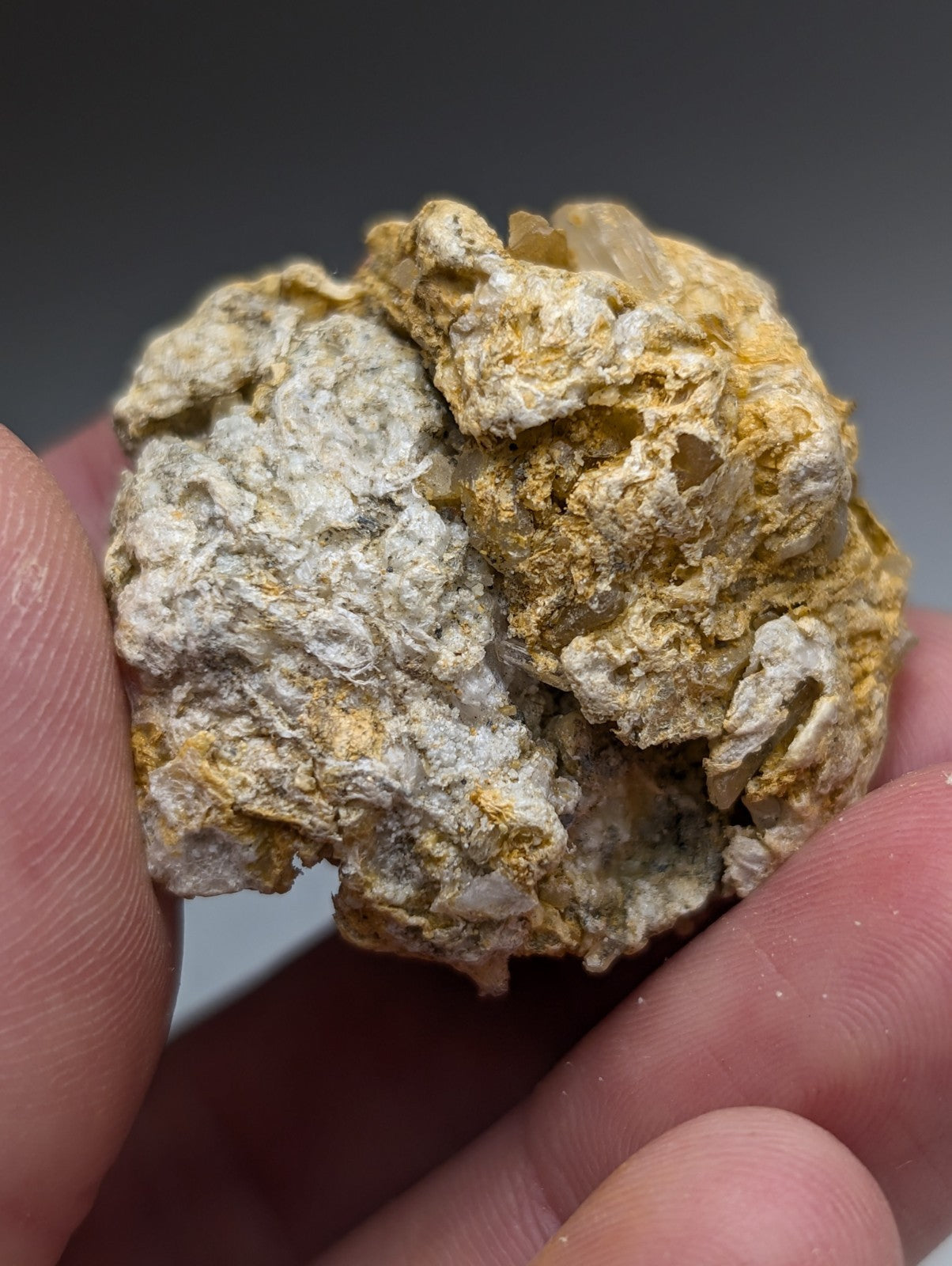 A textured solution quartz mineral with pale gray and golden yellow hues in rectorite from jeffrey quarry arkansas