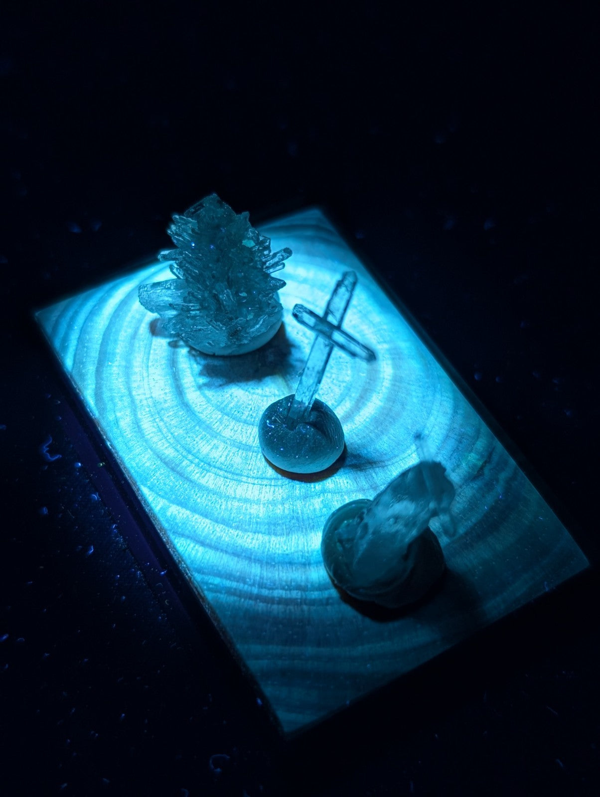 A translucent blue crystal cluster with sharp, jagged edges sits atop a circular base on a wooden surface.