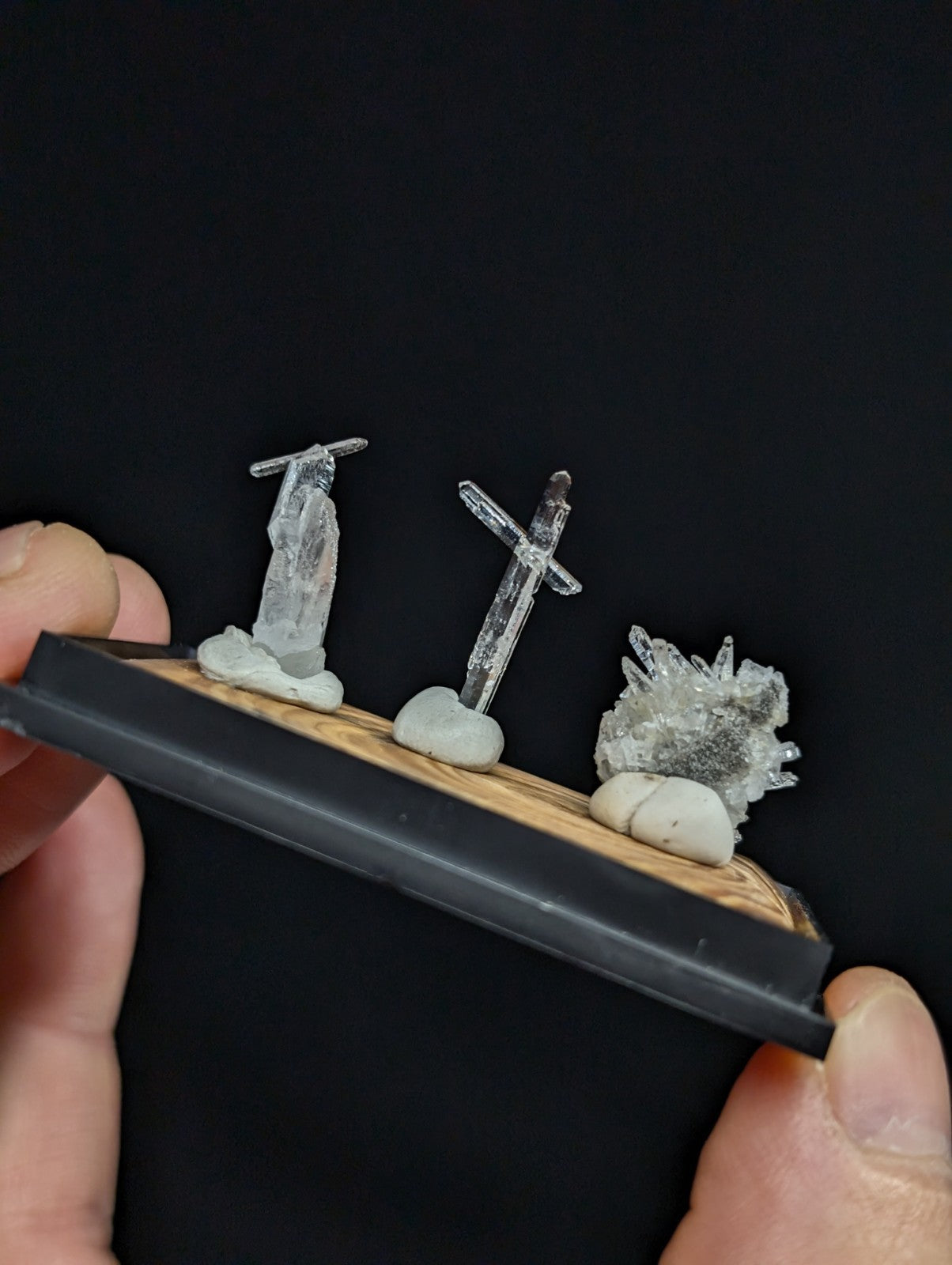 A clear, translucent crystal figurine set on a wooden base with black trim.