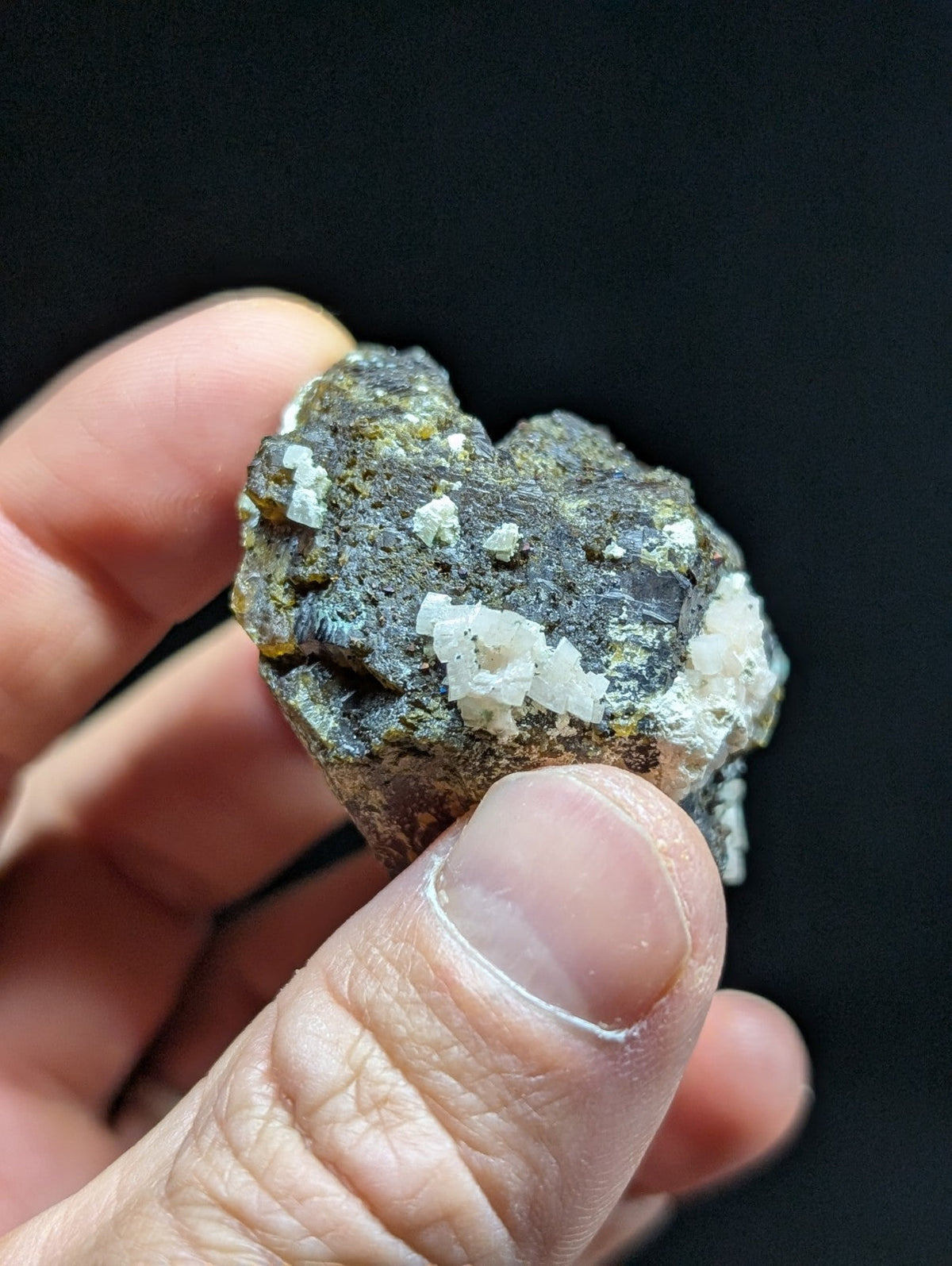 A rugged, dark gray rock specimen with prominent white crystalline formations.
