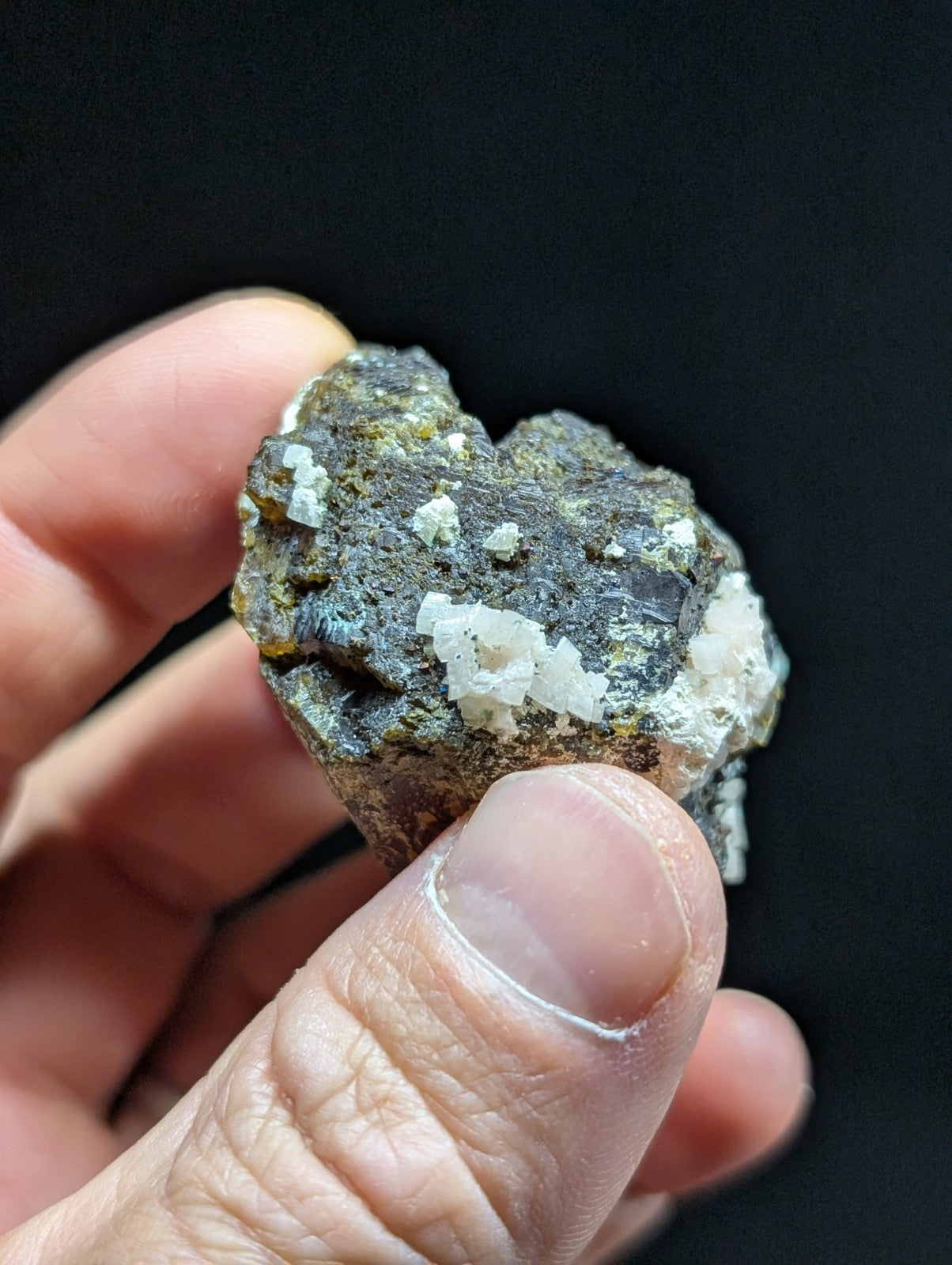 A rugged, dark gray rock specimen with prominent white crystalline formations.