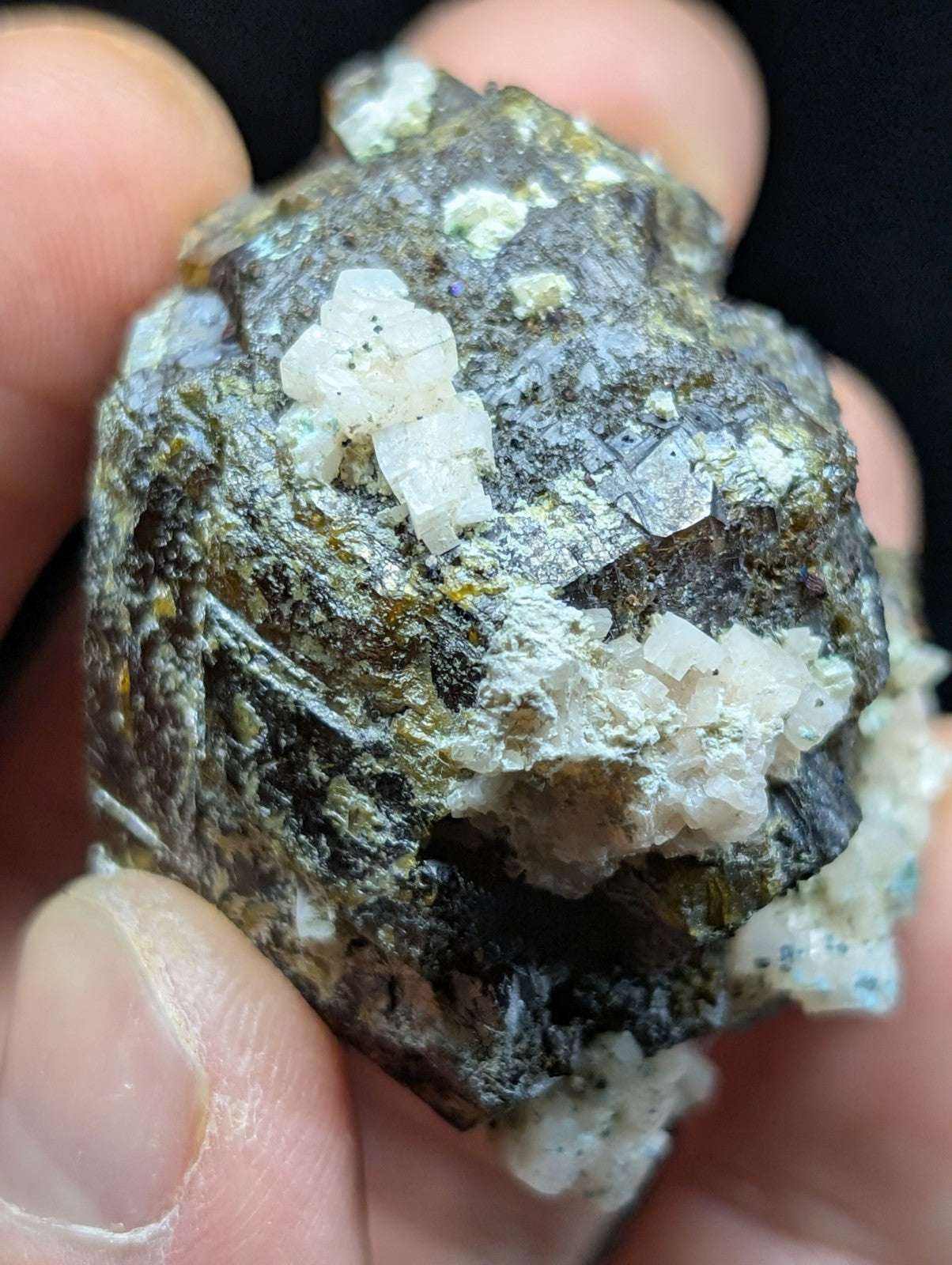 A rough, irregularly shaped mineral specimen with a dark gray matrix and prominent white crystalline formations.
