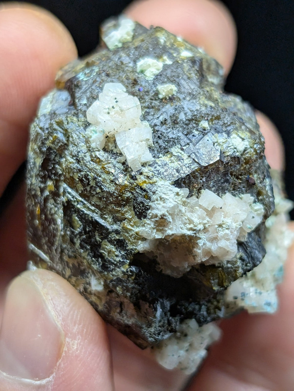 A rough, irregularly shaped mineral specimen with a dark gray matrix and prominent white crystalline formations.