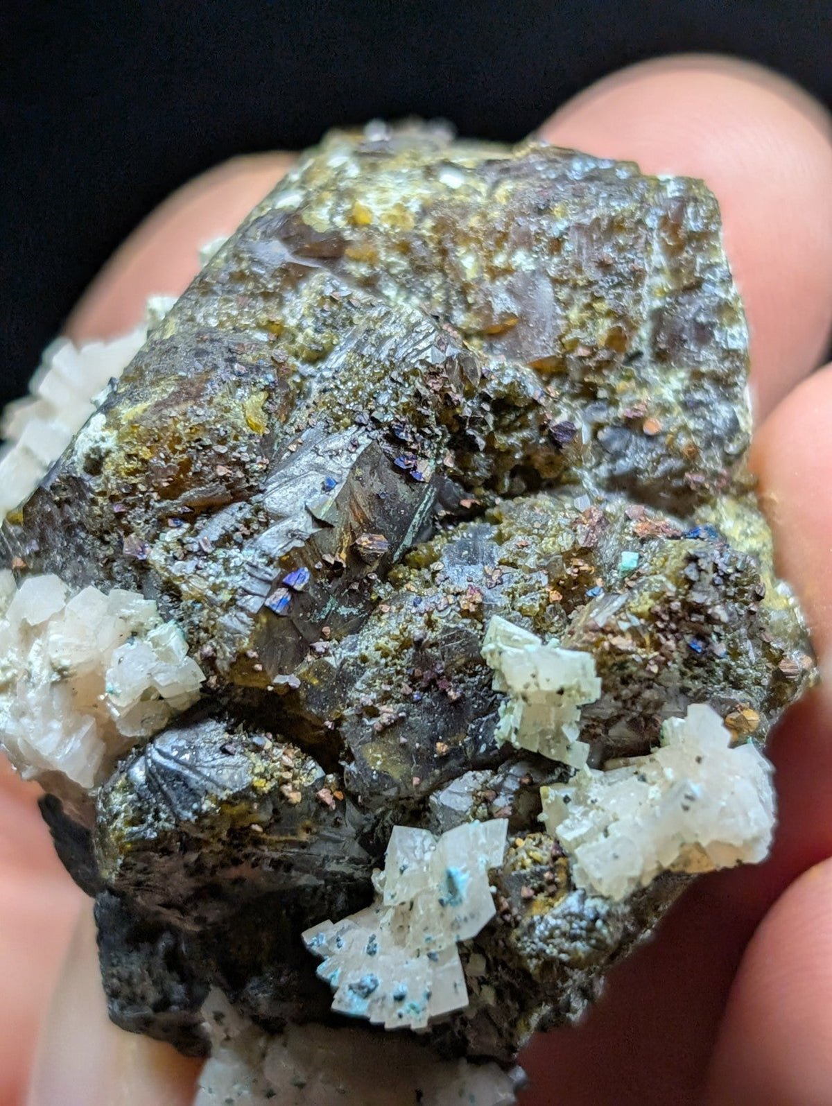 A rugged, dark mineral specimen with translucent white crystals and iridescent blue flecks.