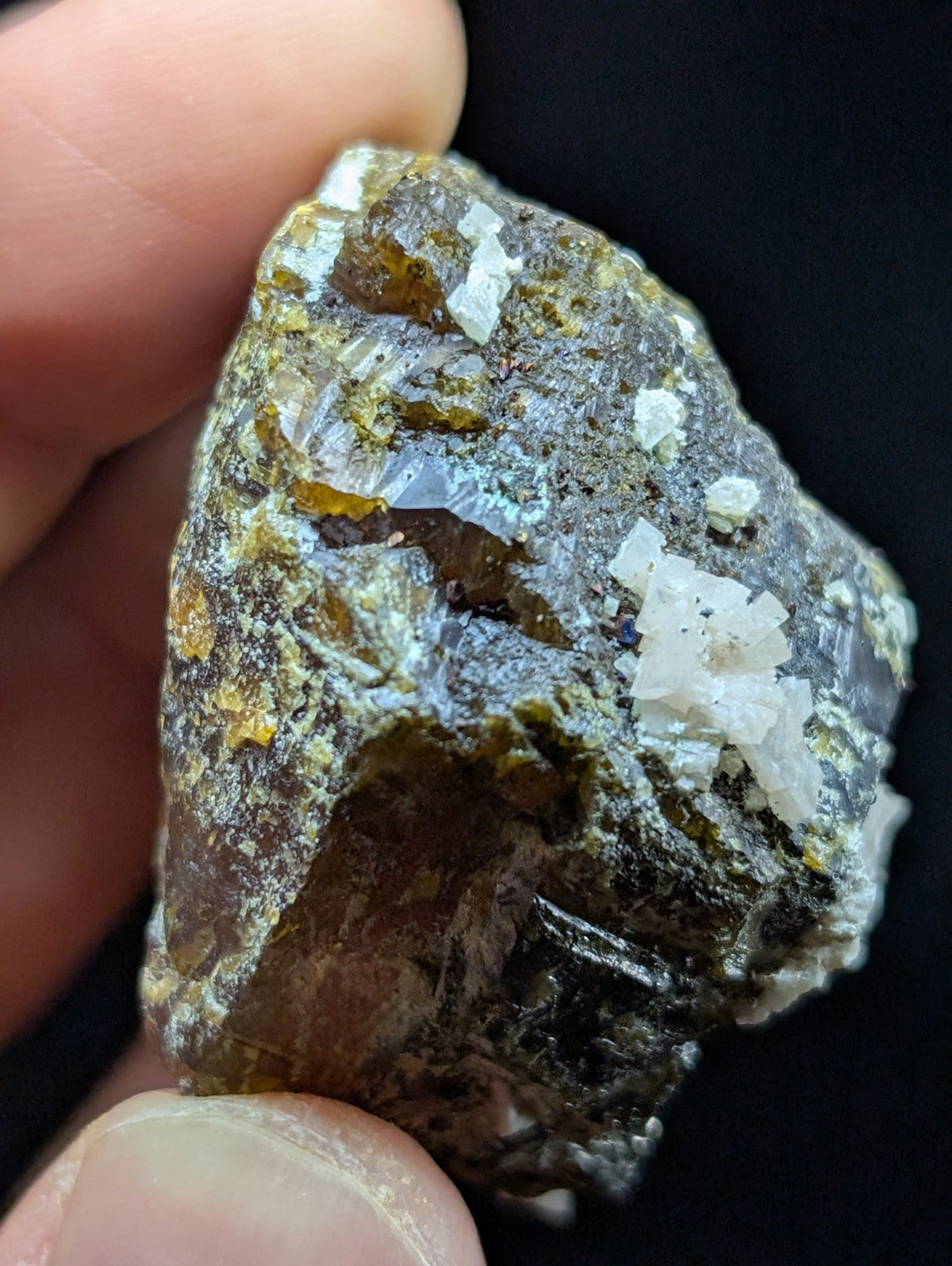 A rough, irregularly shaped mineral specimen with a dark gray base and patches of translucent white crystals interspersed with yellowish inclusions.