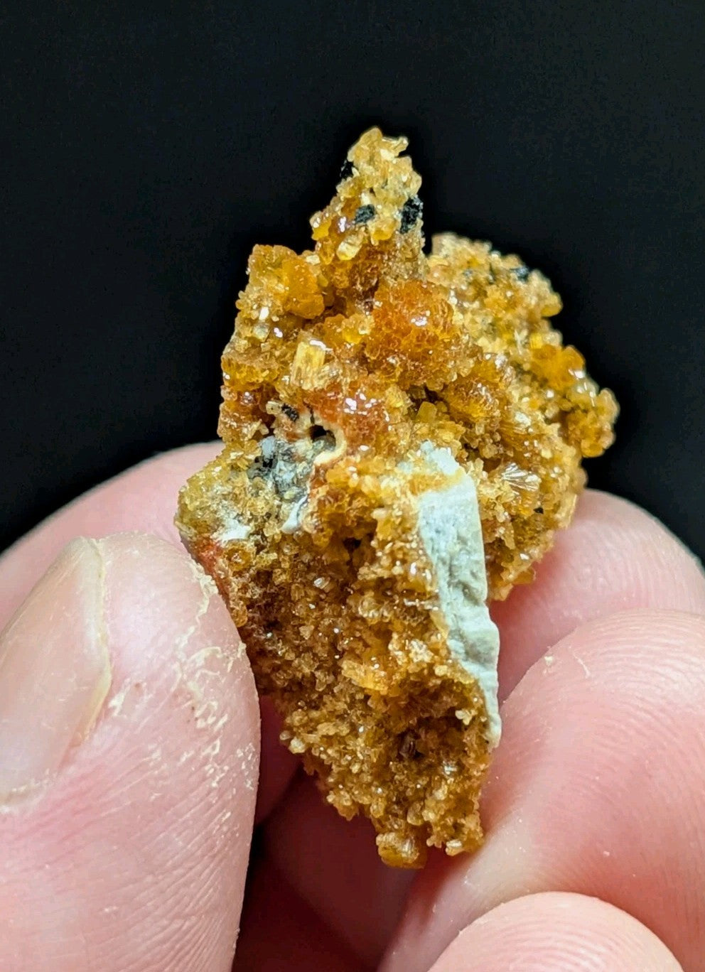 A textured, amber-orange mineral specimen with crystalline formations and a patch of pale greenish-blue material.