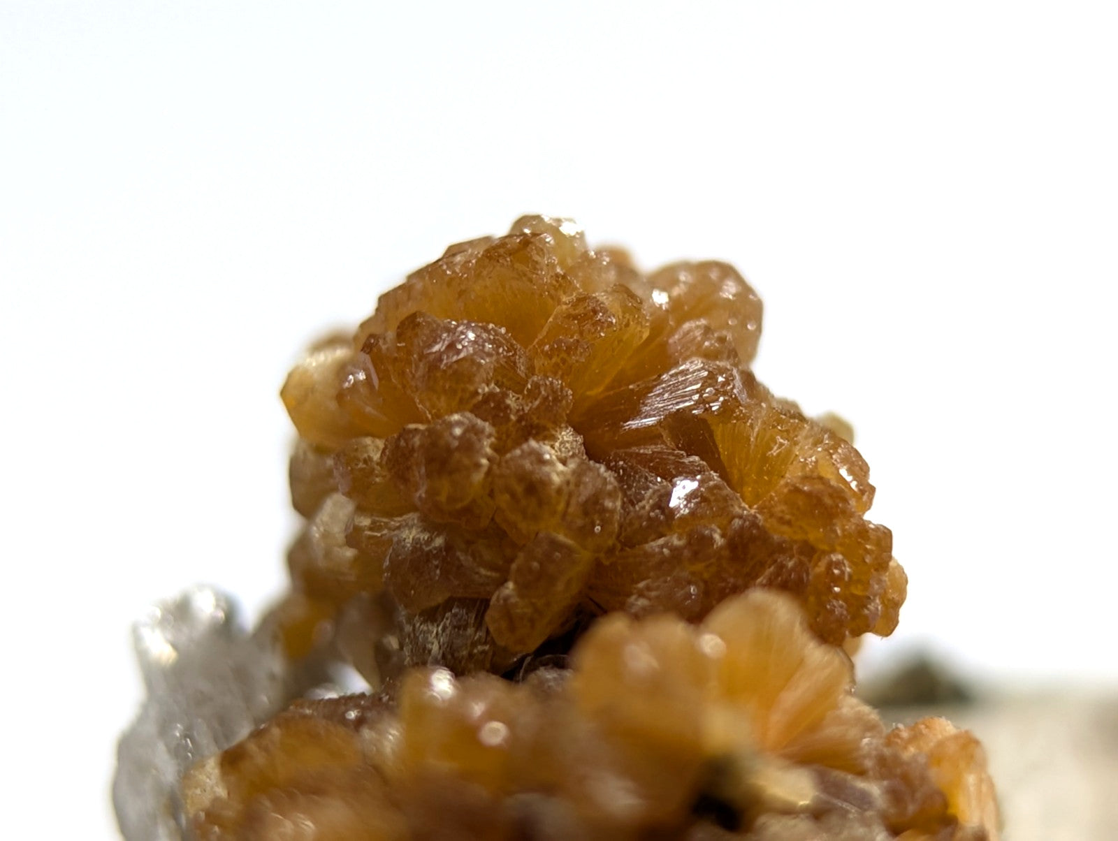 Amber-colored, translucent crystal cluster with a glossy surface and intricate, interlocking formations.