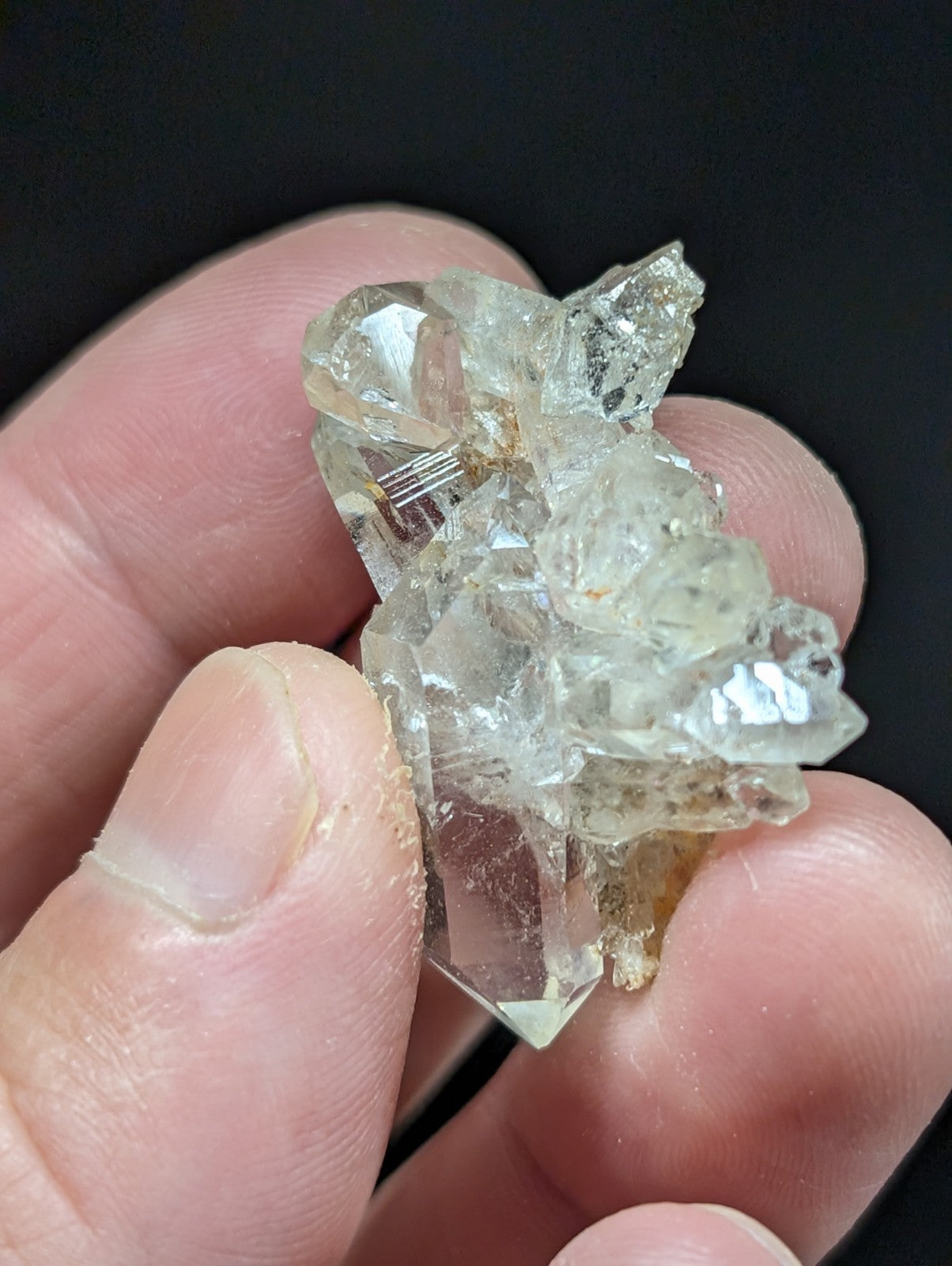A translucent, clear quartz crystal cluster with sharp facets and a few golden inclusions.