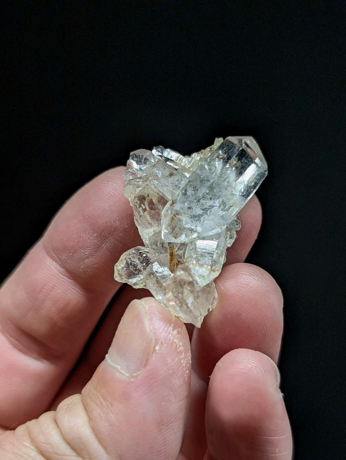 A translucent, clear quartz crystal cluster with sharp facets and a slightly cloudy appearance.