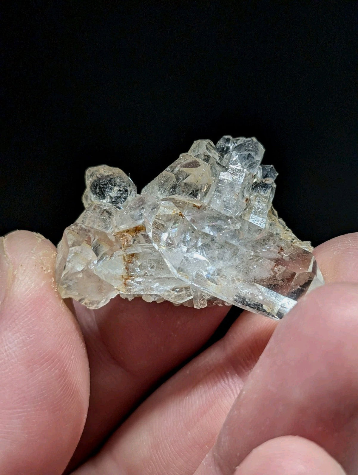 A cluster of translucent, clear quartz crystals with subtle golden and brown inclusions.
