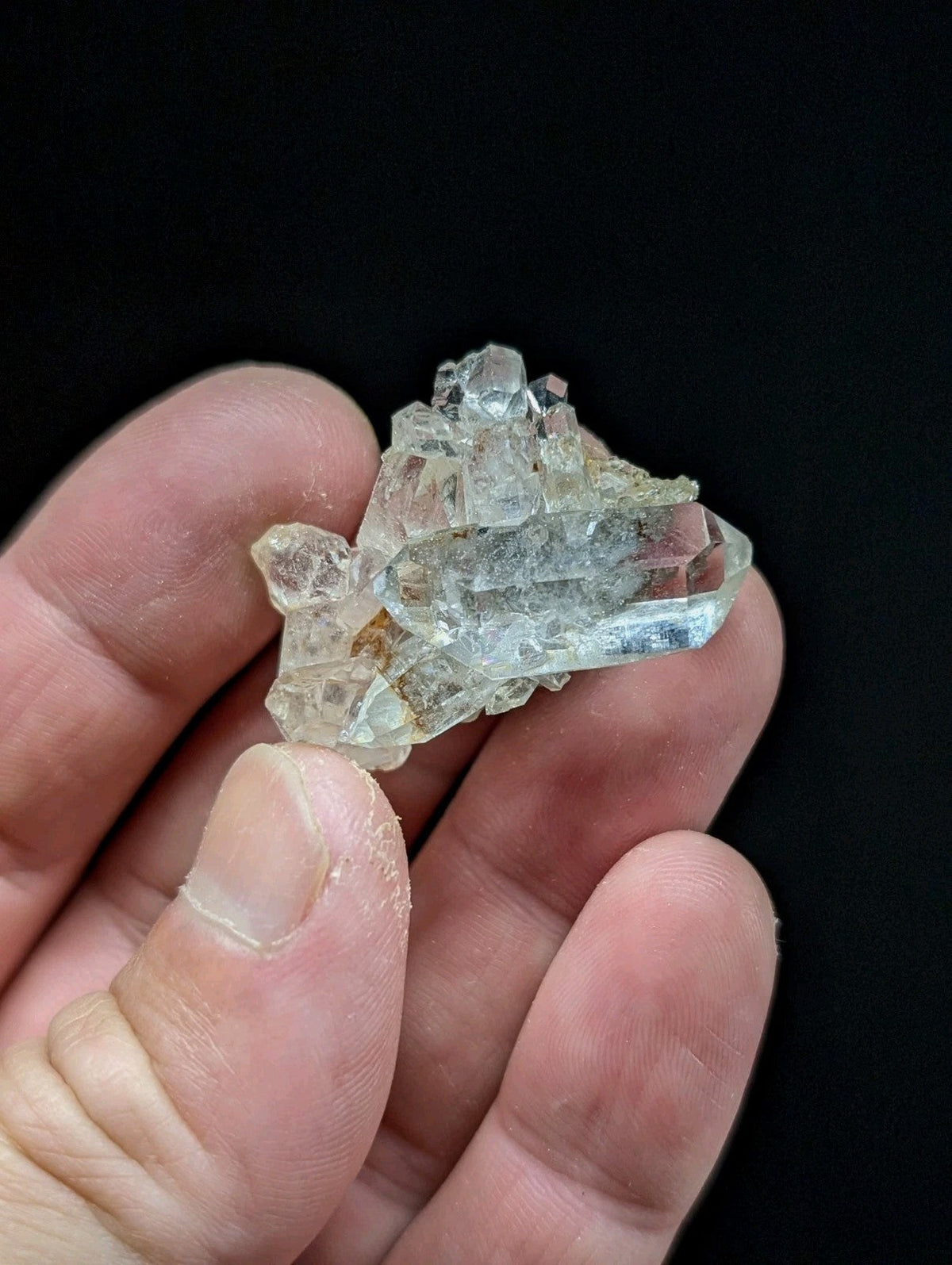 A translucent, pale blue-green quartz crystal cluster with sharp facets and a rough, natural base.