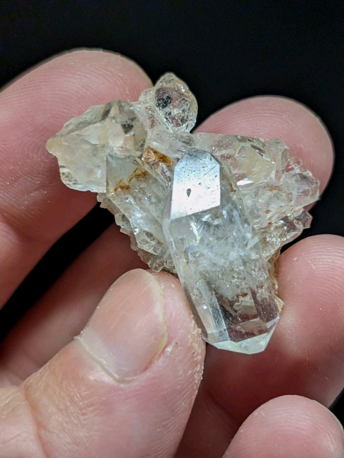 A translucent, pale quartz crystal cluster with a prominent central prism and smaller surrounding crystals.