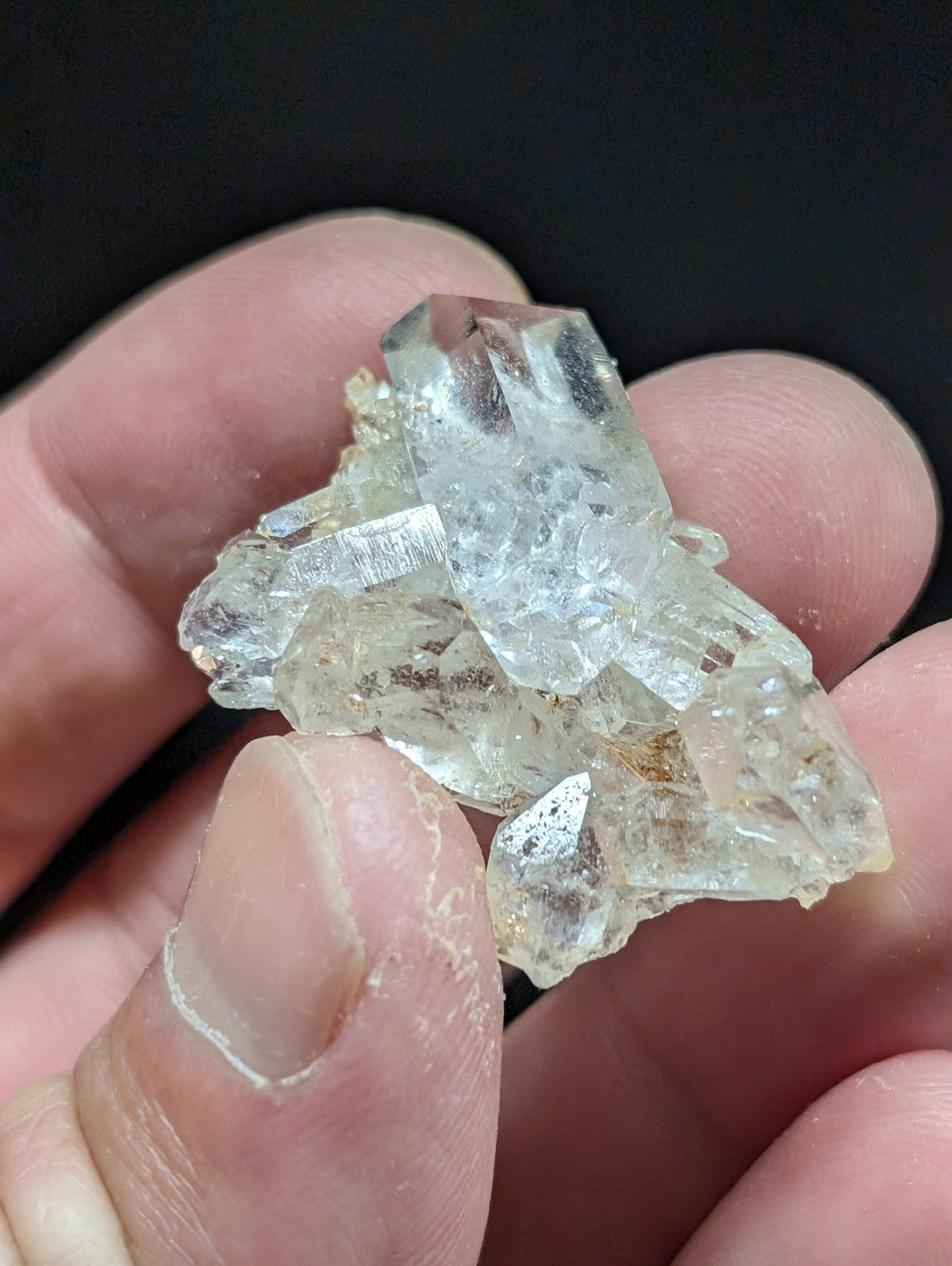 A cluster of clear, translucent quartz crystals with sharp facets and subtle internal inclusions.