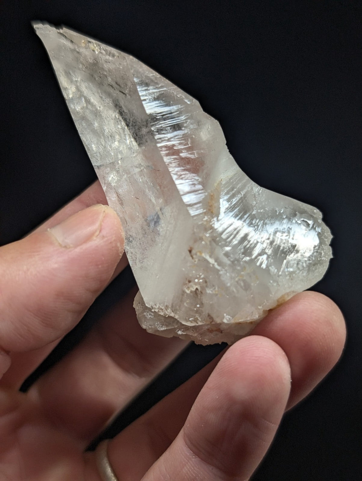 A translucent, clear quartz crystal with a pointed tip and visible internal striations.
