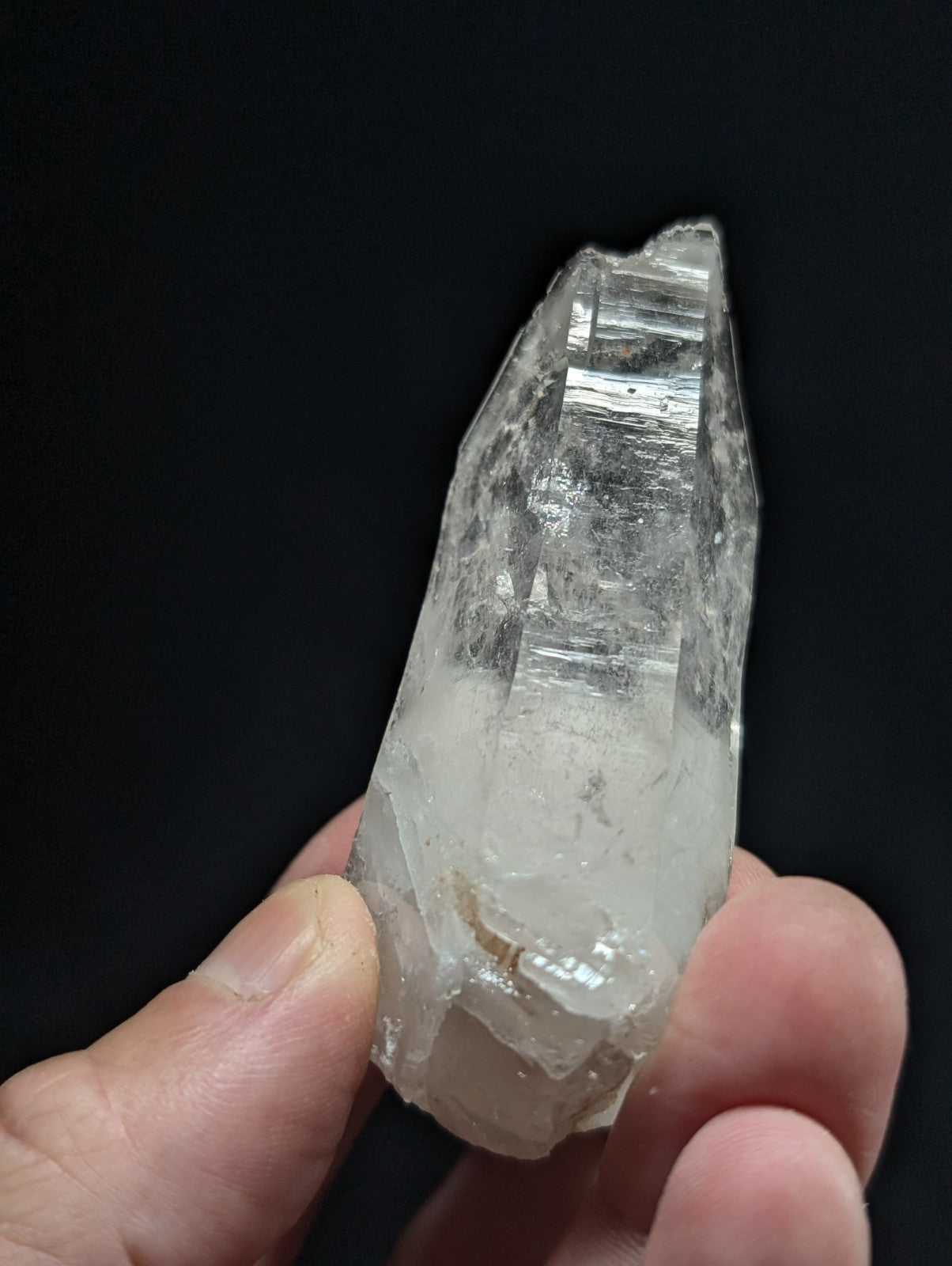 A translucent, clear quartz crystal with a pointed tip and visible internal striations.