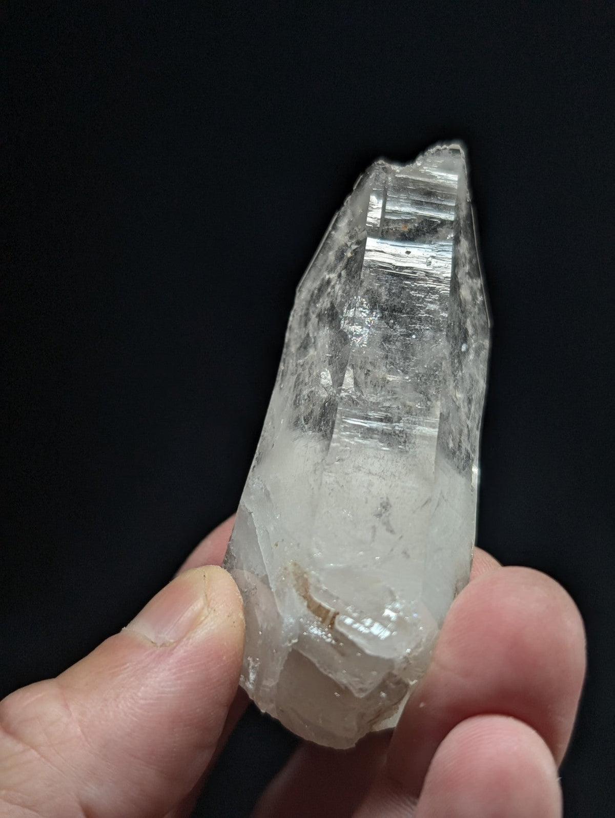 A translucent, clear quartz crystal with a pointed tip and visible internal striations.