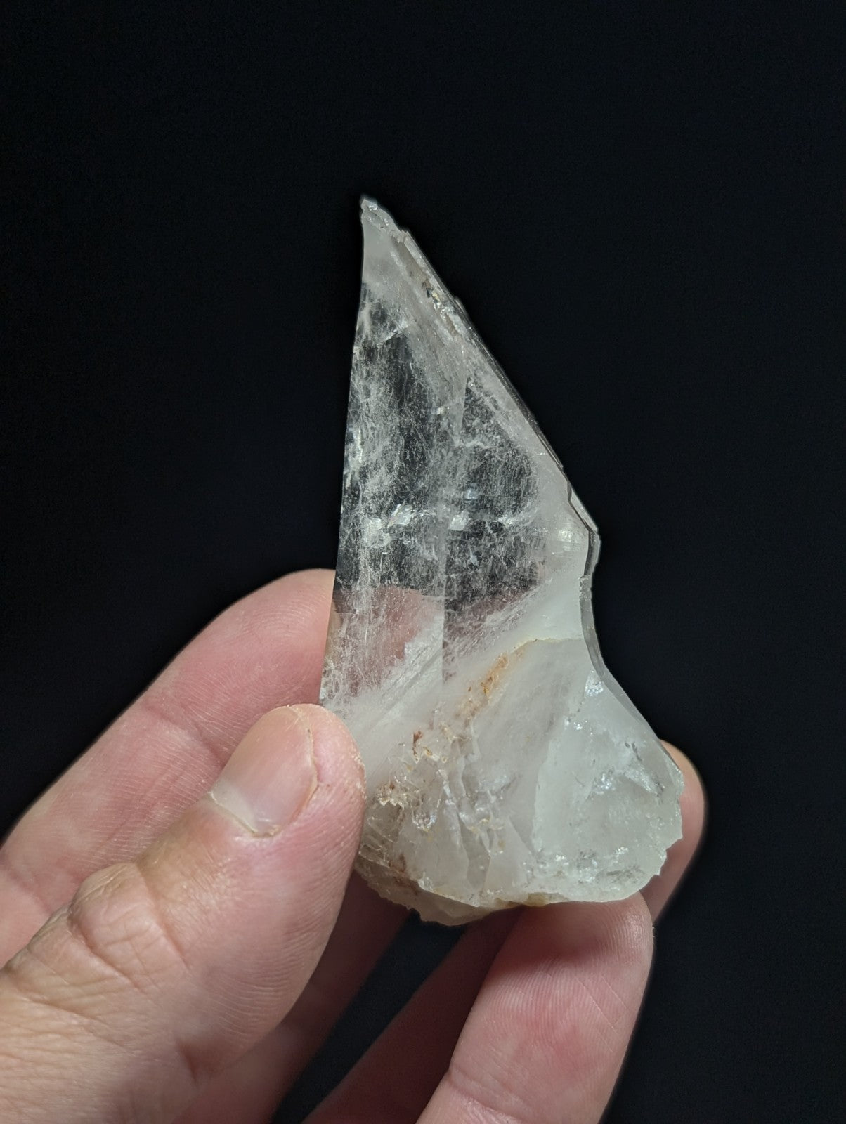 A translucent, irregularly shaped crystal fragment with a pale, milky white hue and subtle internal veining.