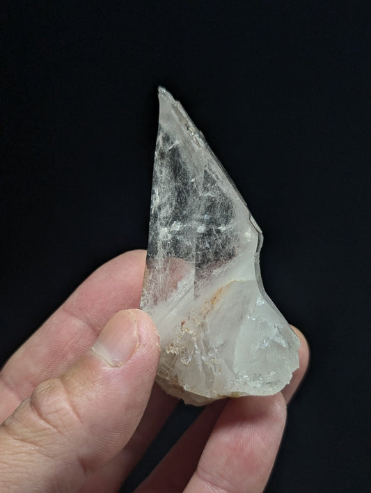 A translucent, irregularly shaped crystal fragment with a pale, milky white hue and subtle internal veining.