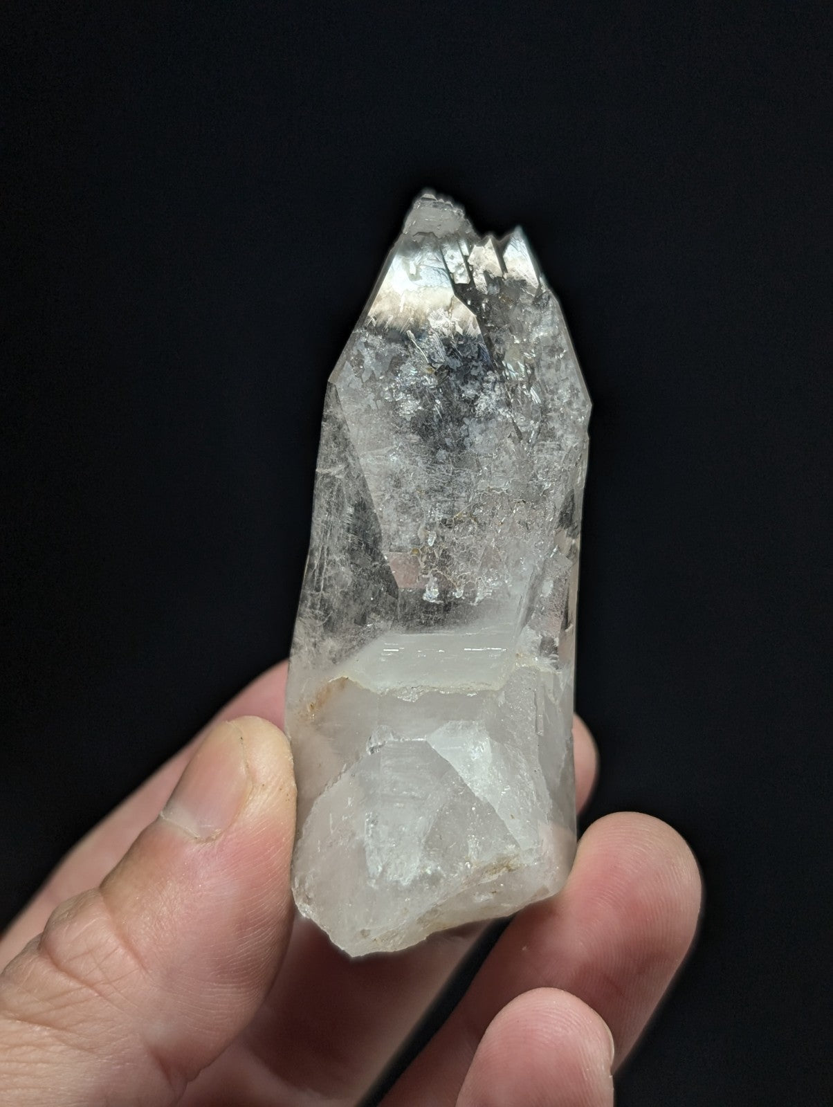 A translucent, clear quartz crystal with a pointed tip and natural facets.