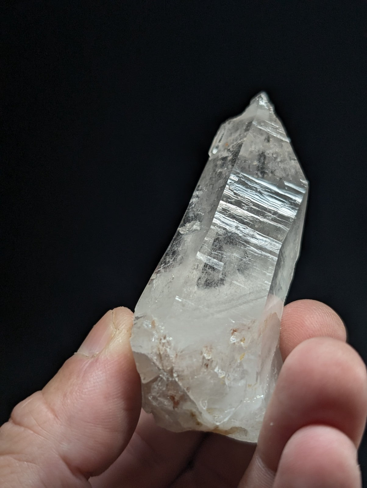 A translucent, clear quartz crystal with visible internal striations and a pointed tip.