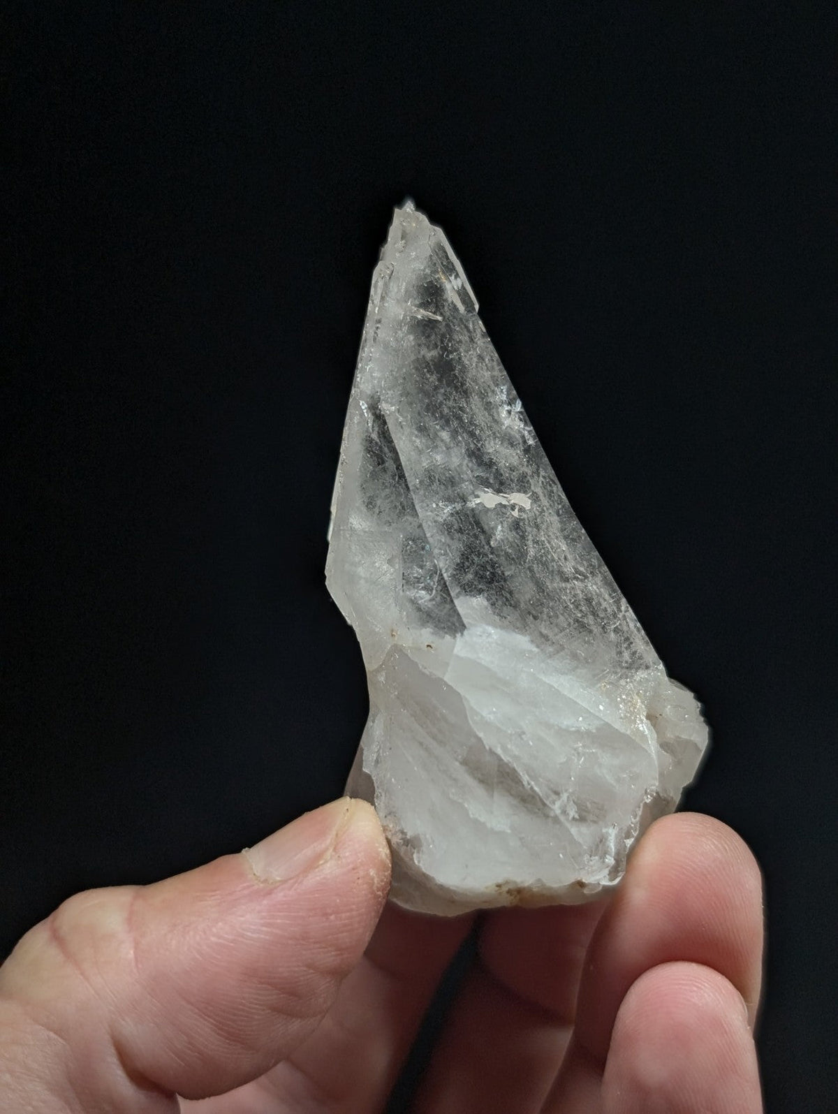 A translucent, clear quartz crystal with a pointed tip and natural facets.