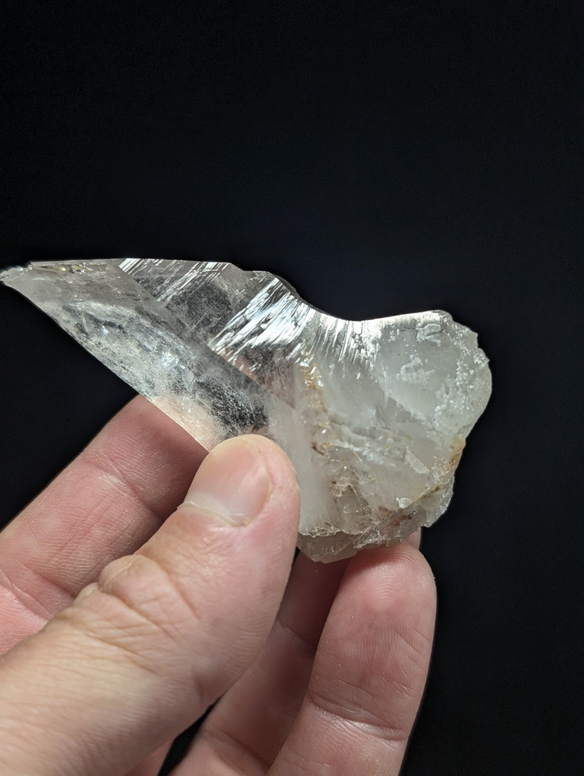 A translucent, clear quartz crystal with a jagged, natural edge and subtle internal striations.