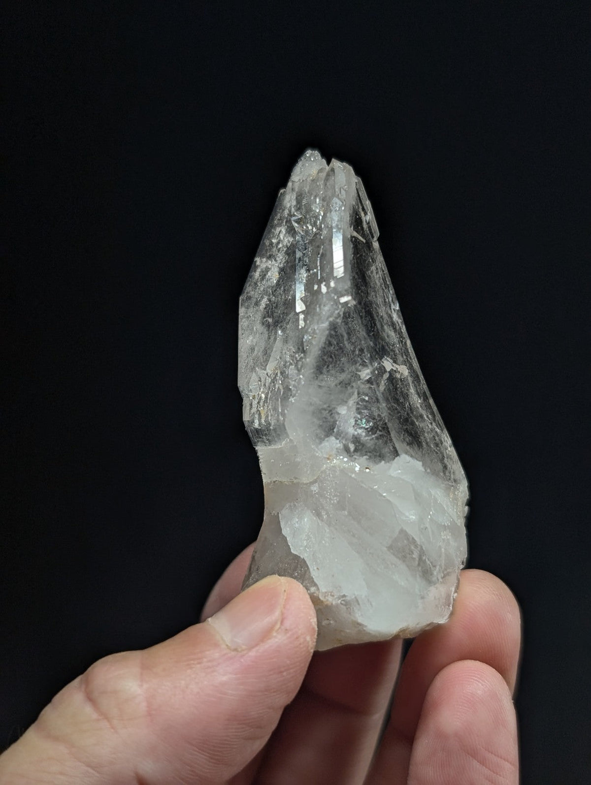 A translucent, clear quartz crystal with a pointed tip and visible internal striations.
