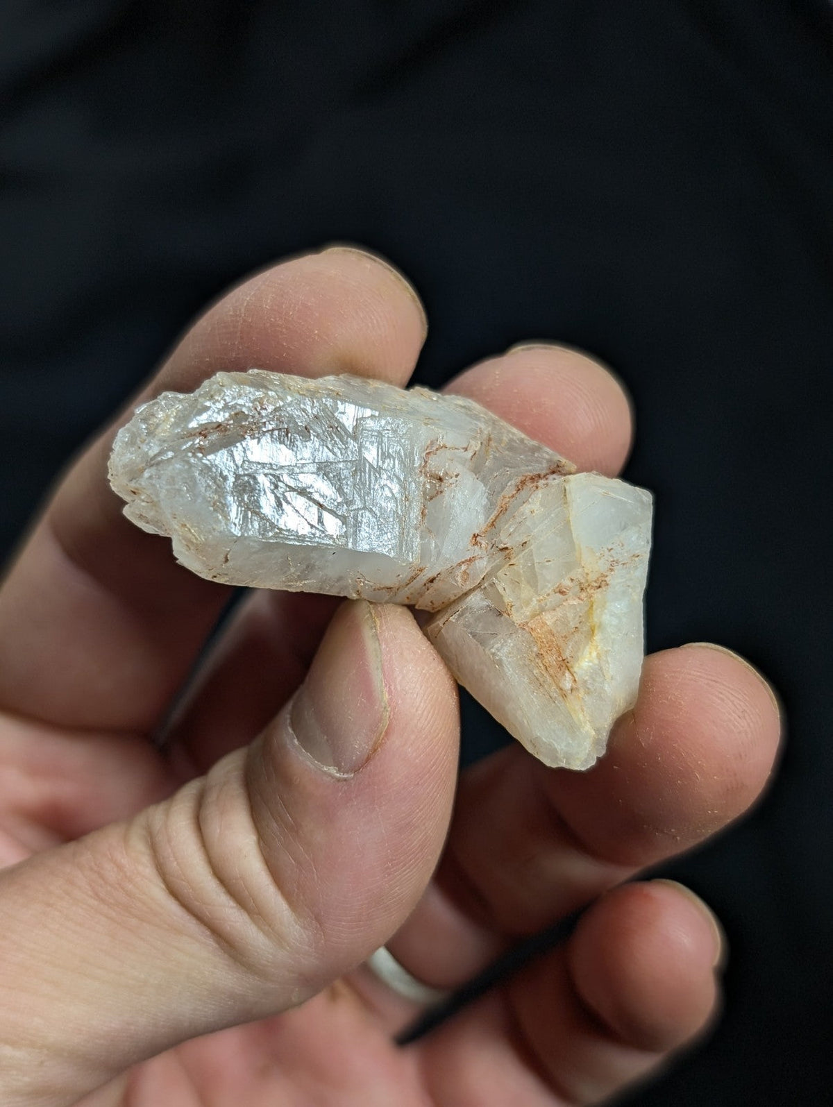 A translucent, pale quartz crystal with natural facets and subtle orange inclusions.