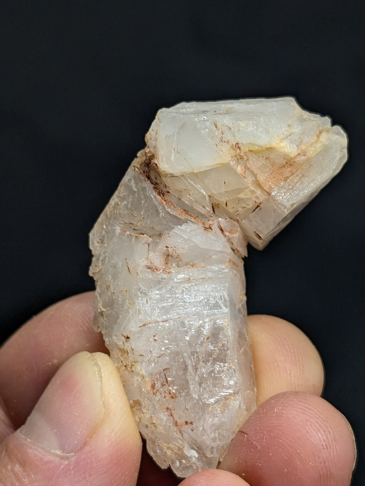 A translucent, pale white quartz crystal with visible internal striations and faint brownish mineral inclusions.
