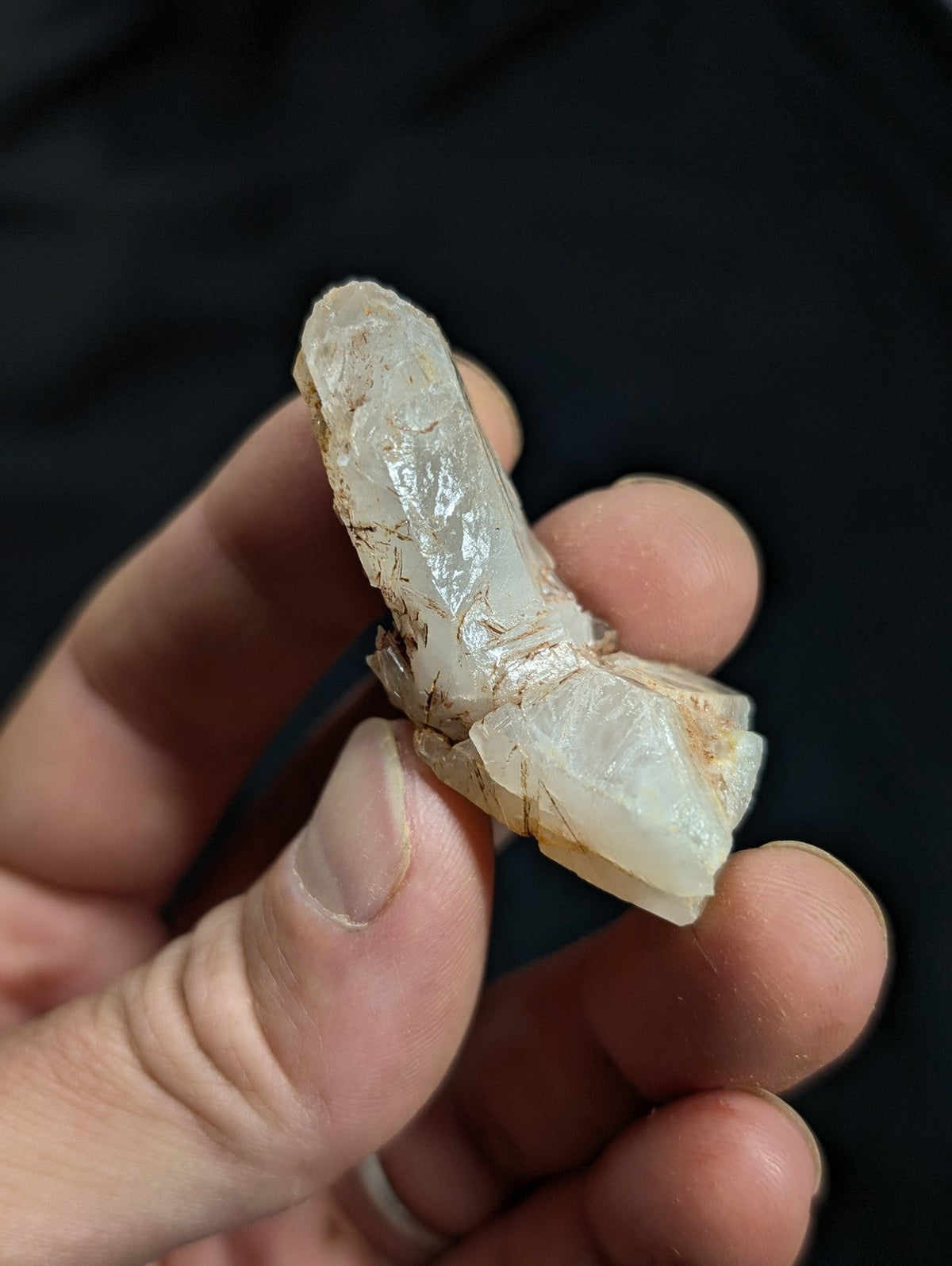 A translucent, pale white crystal with natural facets and subtle brownish inclusions.