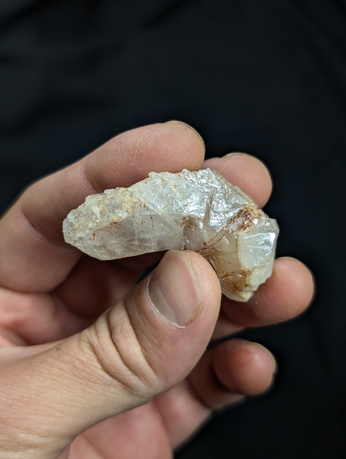 A translucent, pale white crystal with subtle brown inclusions and a rough, natural surface.