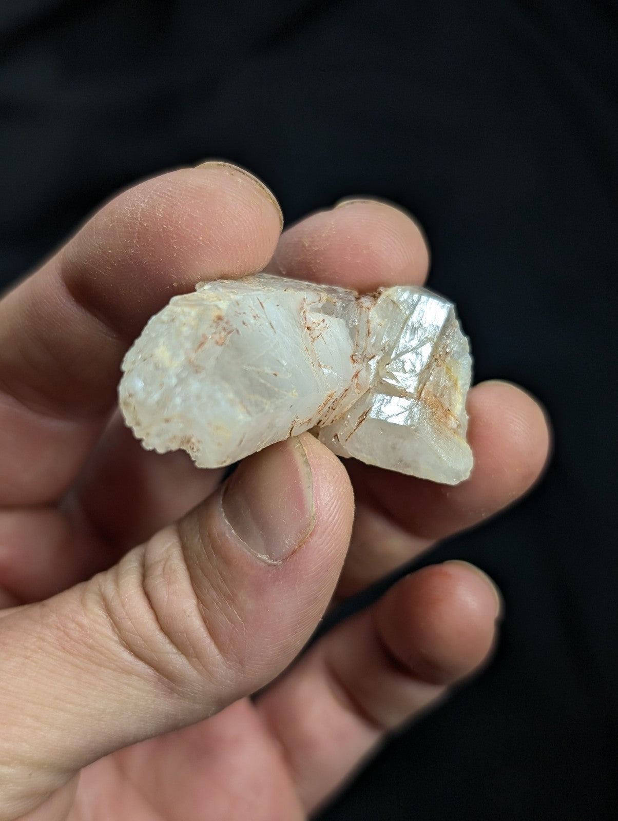A translucent, pale white crystal fragment with visible internal facets and minor brownish inclusions.